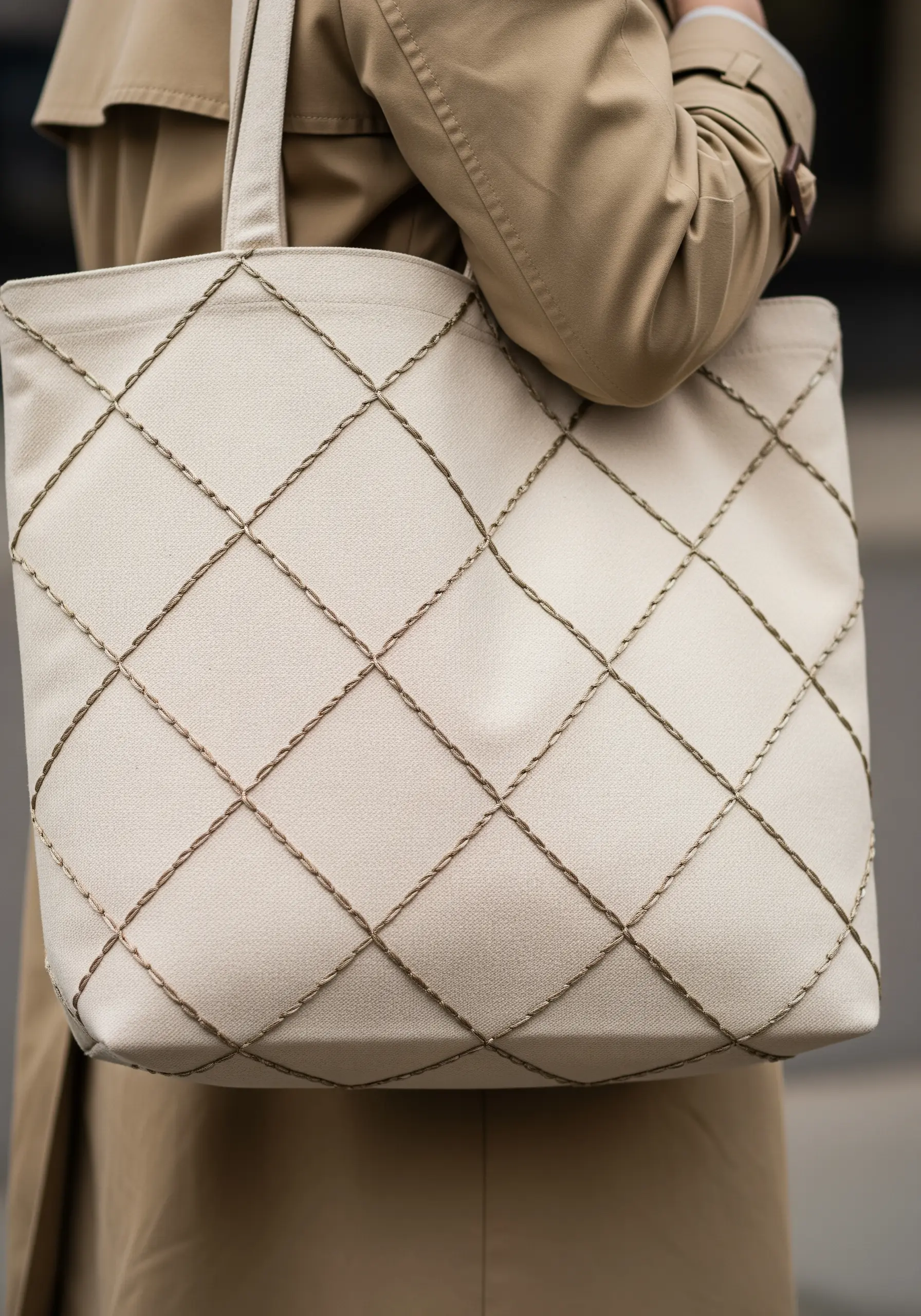 A diamond grid pattern stitched in a raised, rope-like stitch on a cream-colored tote bag.