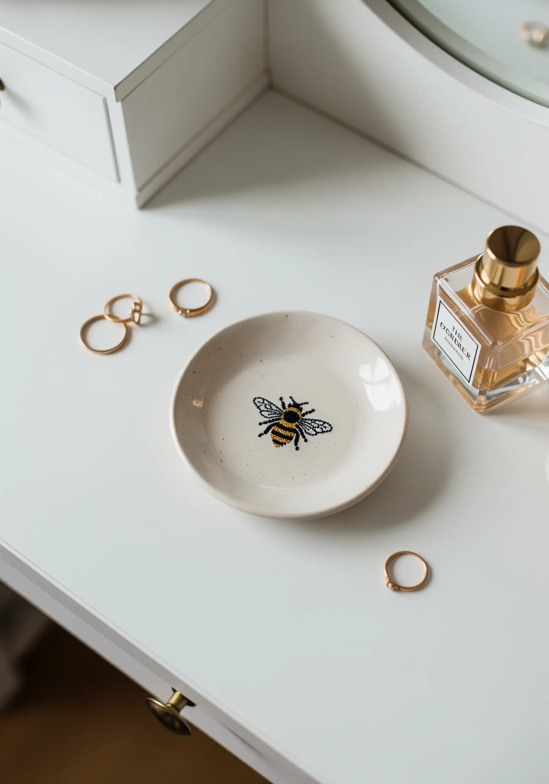 A small ceramic trinket dish featuring a detailed embroidered bee motif sealed in the center.