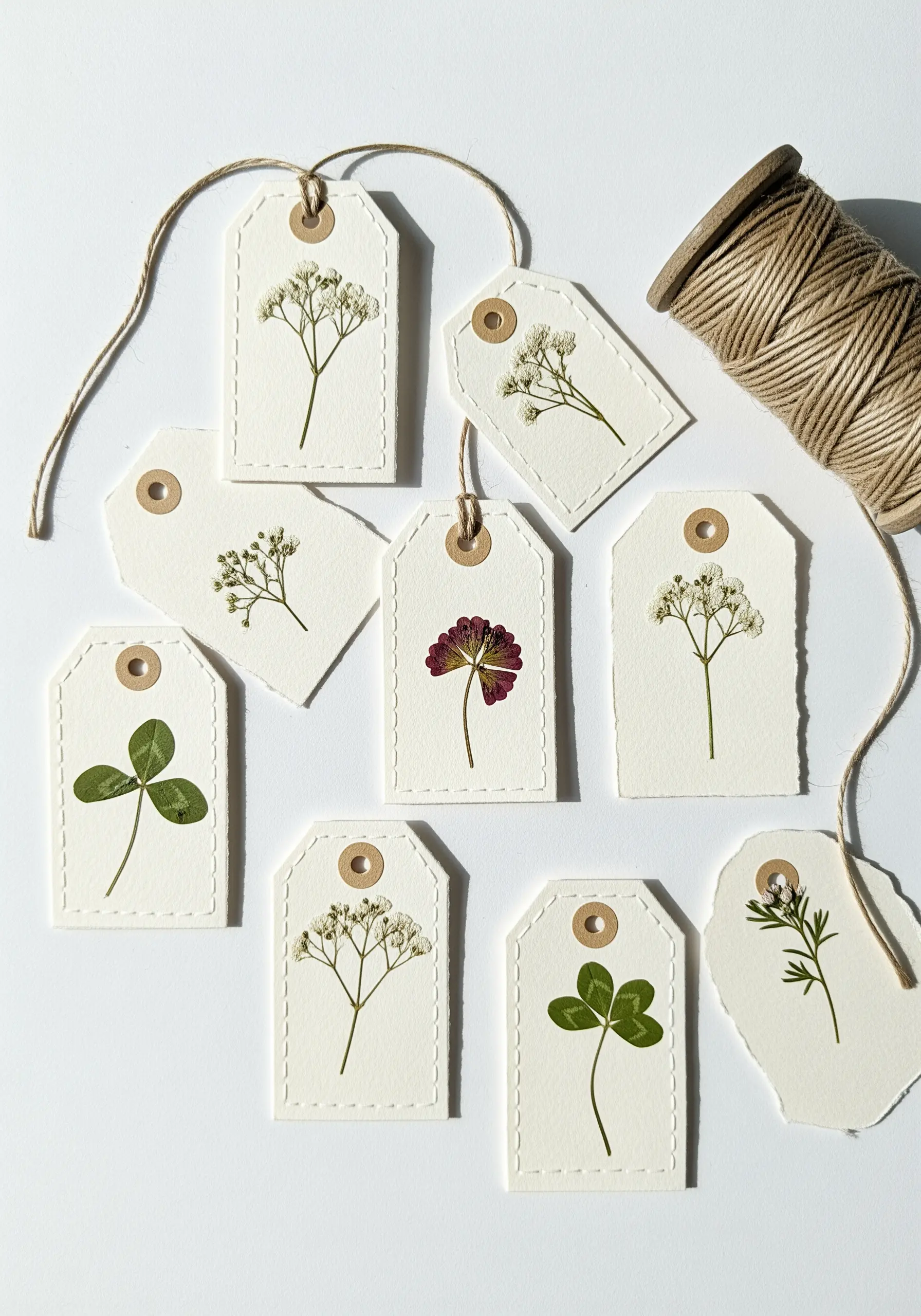 A collection of paper gift tags, each featuring a single pressed or embroidered botanical.