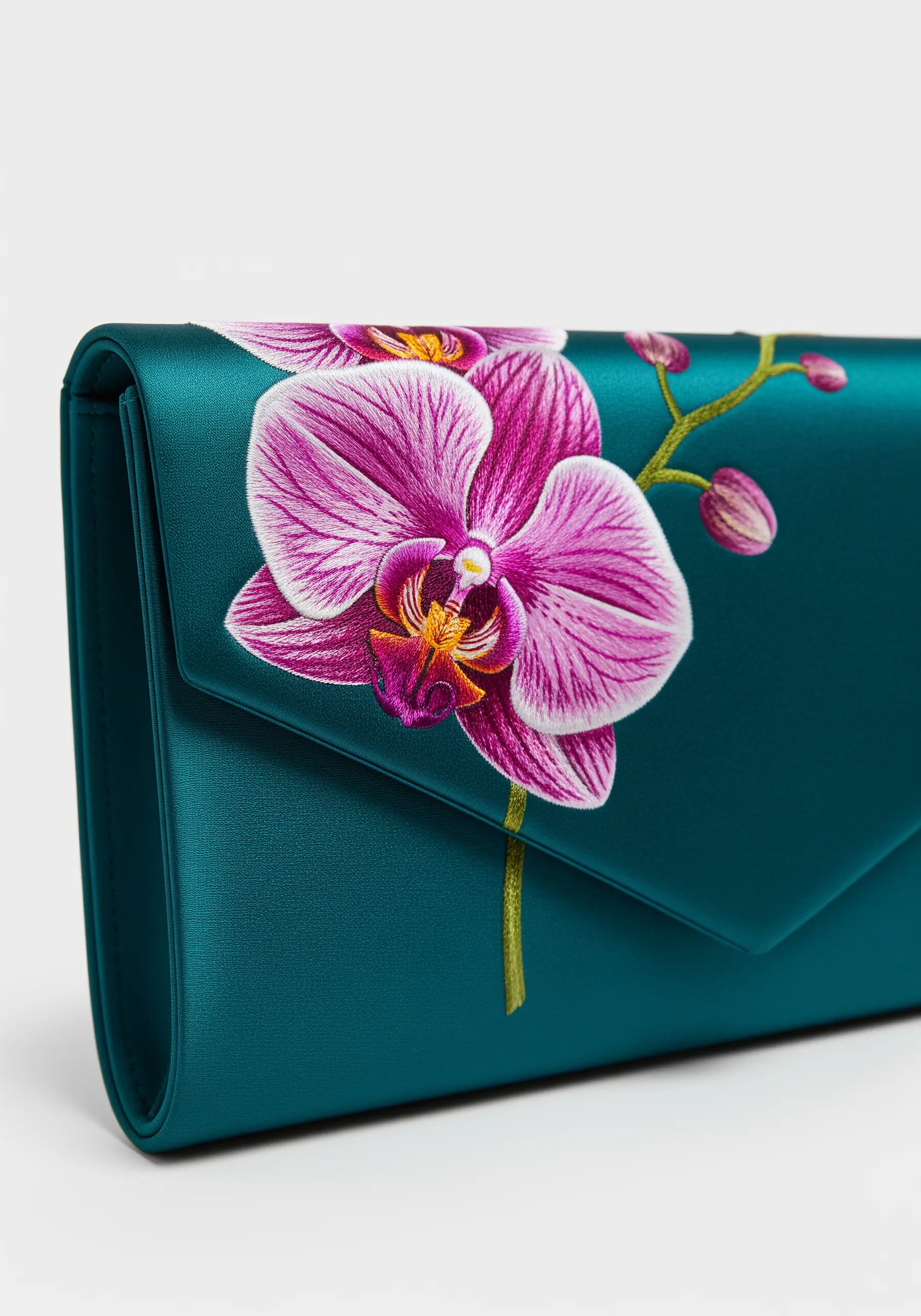 A realistic pink orchid embroidered onto the flap of a teal satin evening clutch.