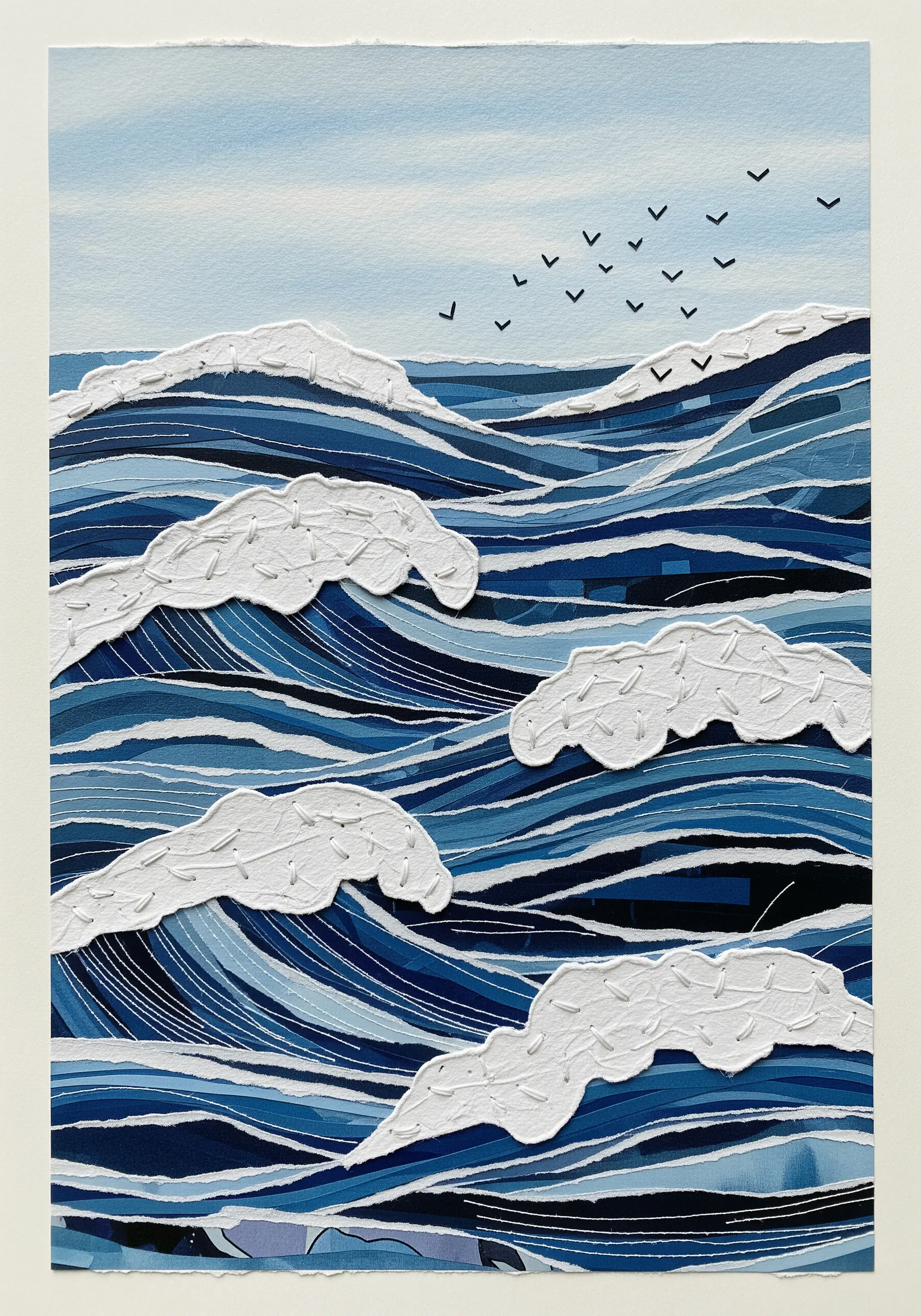 Paper collage of ocean waves with textured white paper for the sea foam.