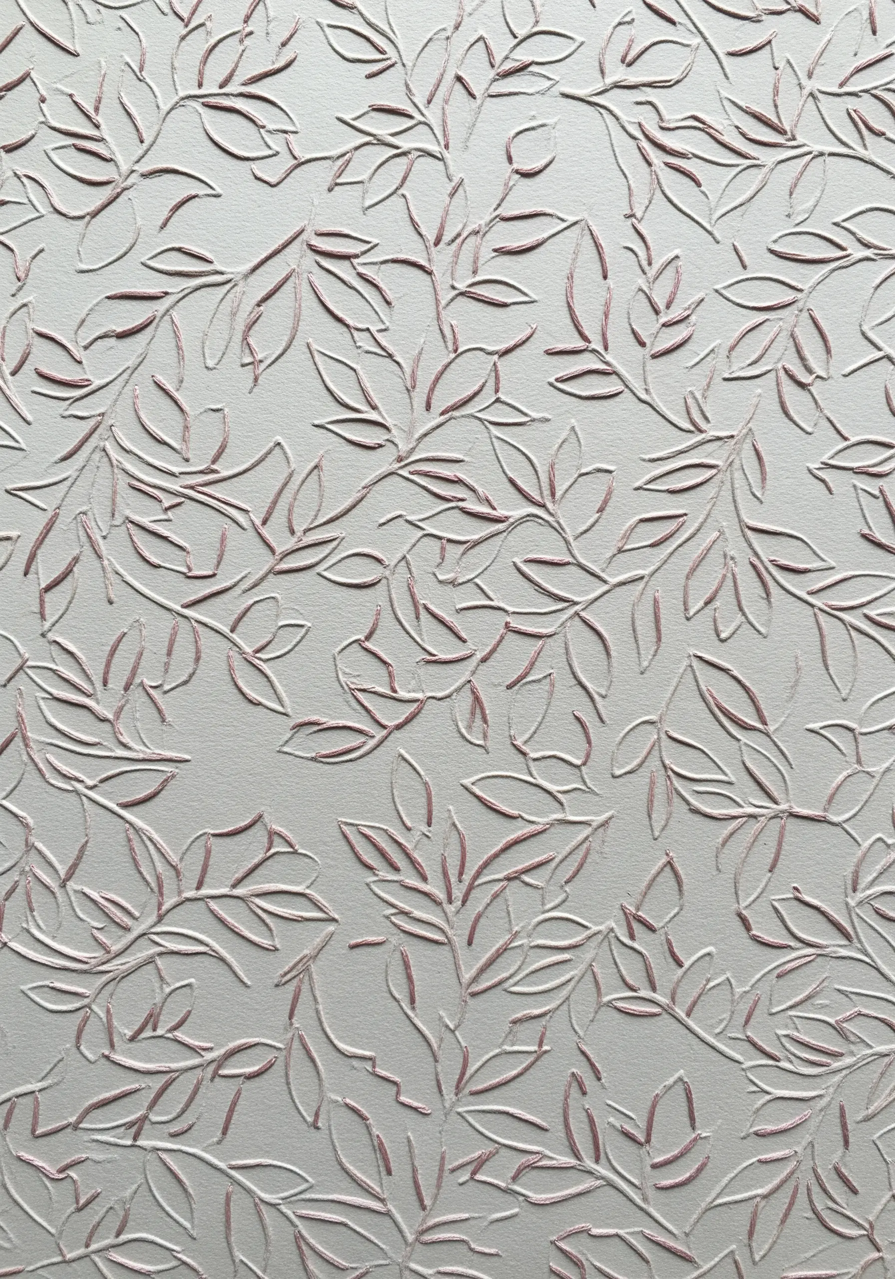 White embossed paper with a leaf pattern traced over with fine pink thread.