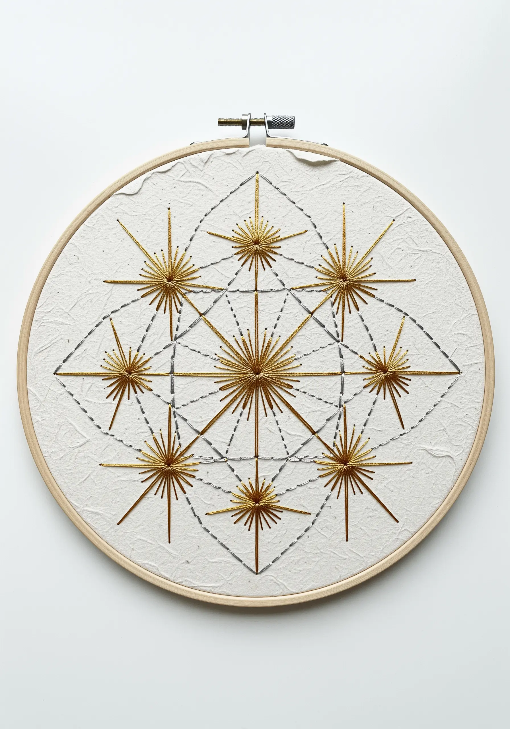 Geometric starbursts stitched in gold metallic thread onto a textured, off-white paper background.