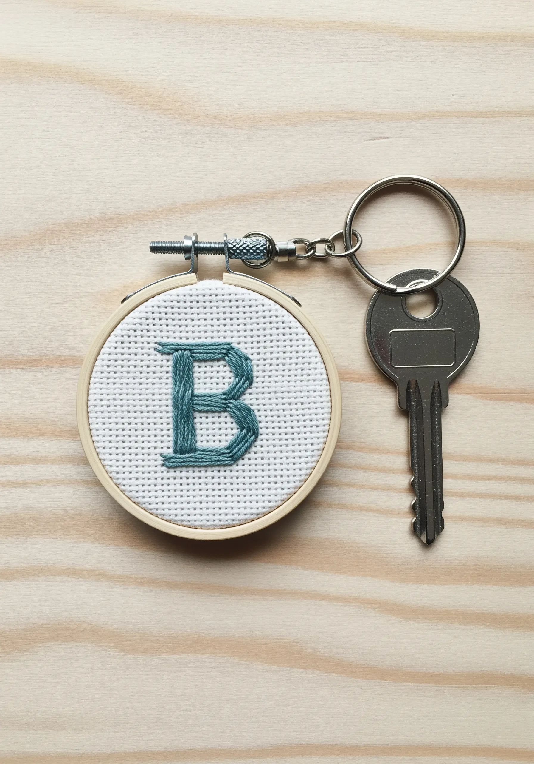 Embroidered teal monogram 'B' on white Aida cloth in a mini hoop keychain