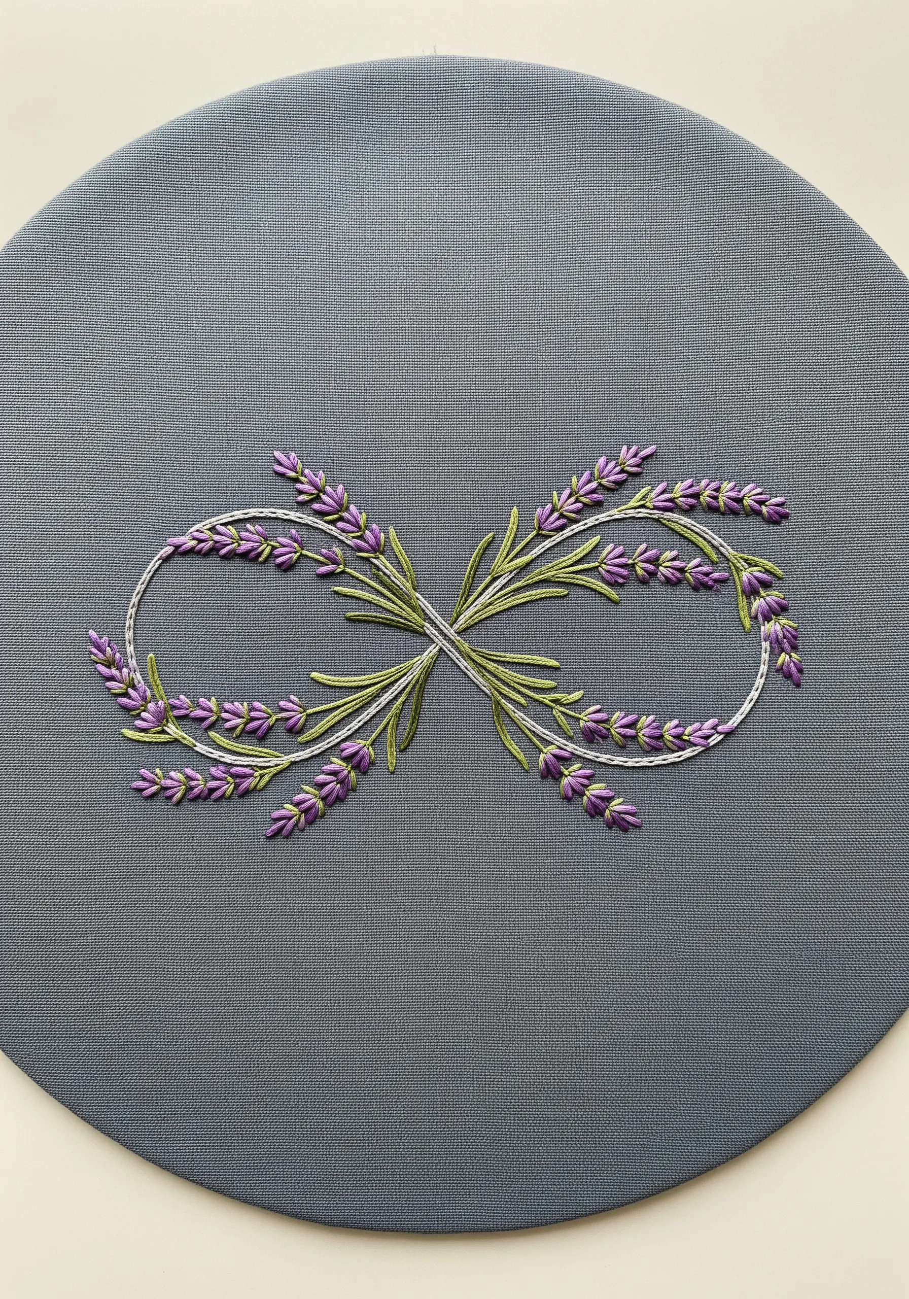An infinity symbol made of embroidered lavender sprigs on a grey placemat.