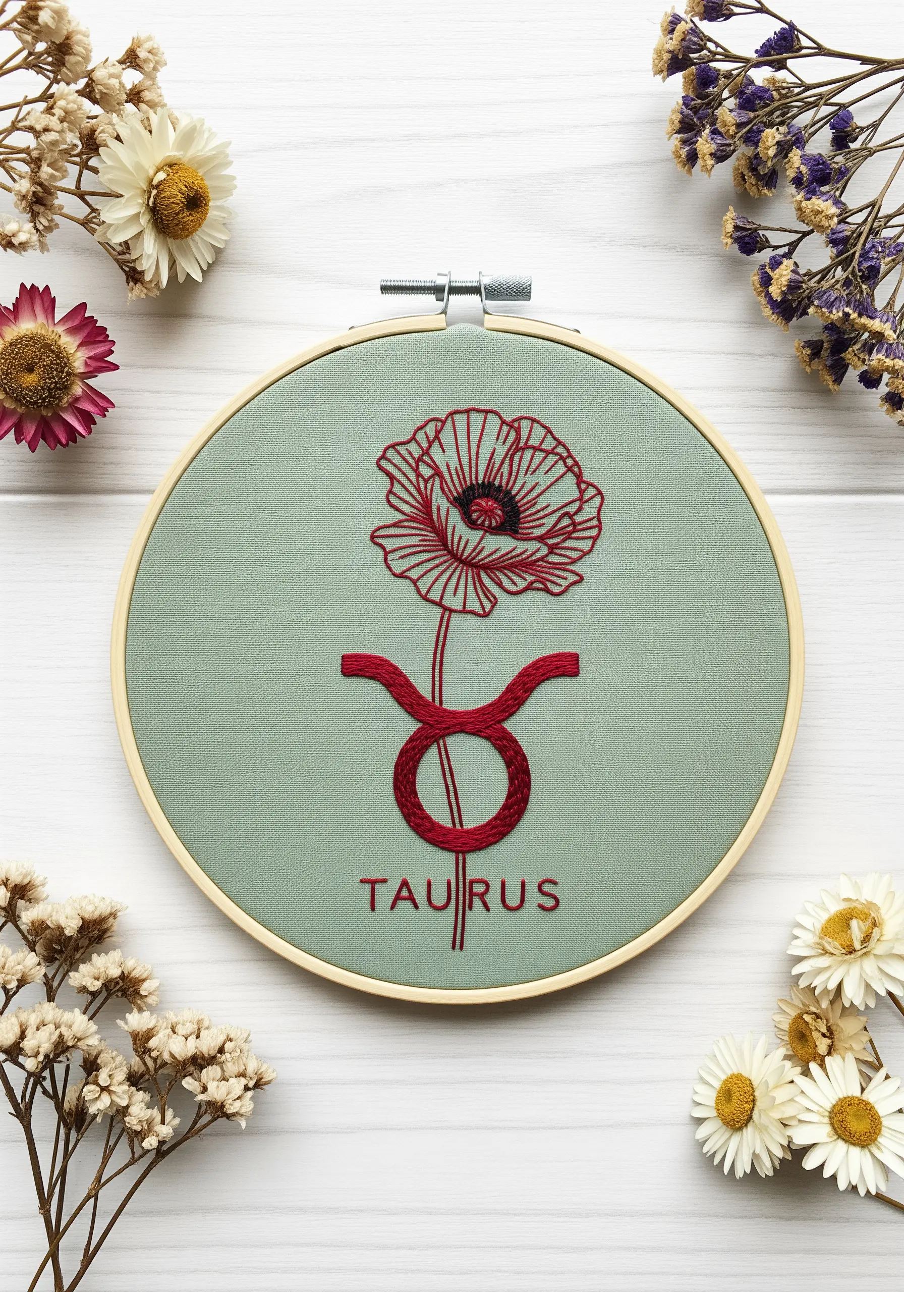 Taurus zodiac symbol embroidered in red, with a poppy flower growing from the top.