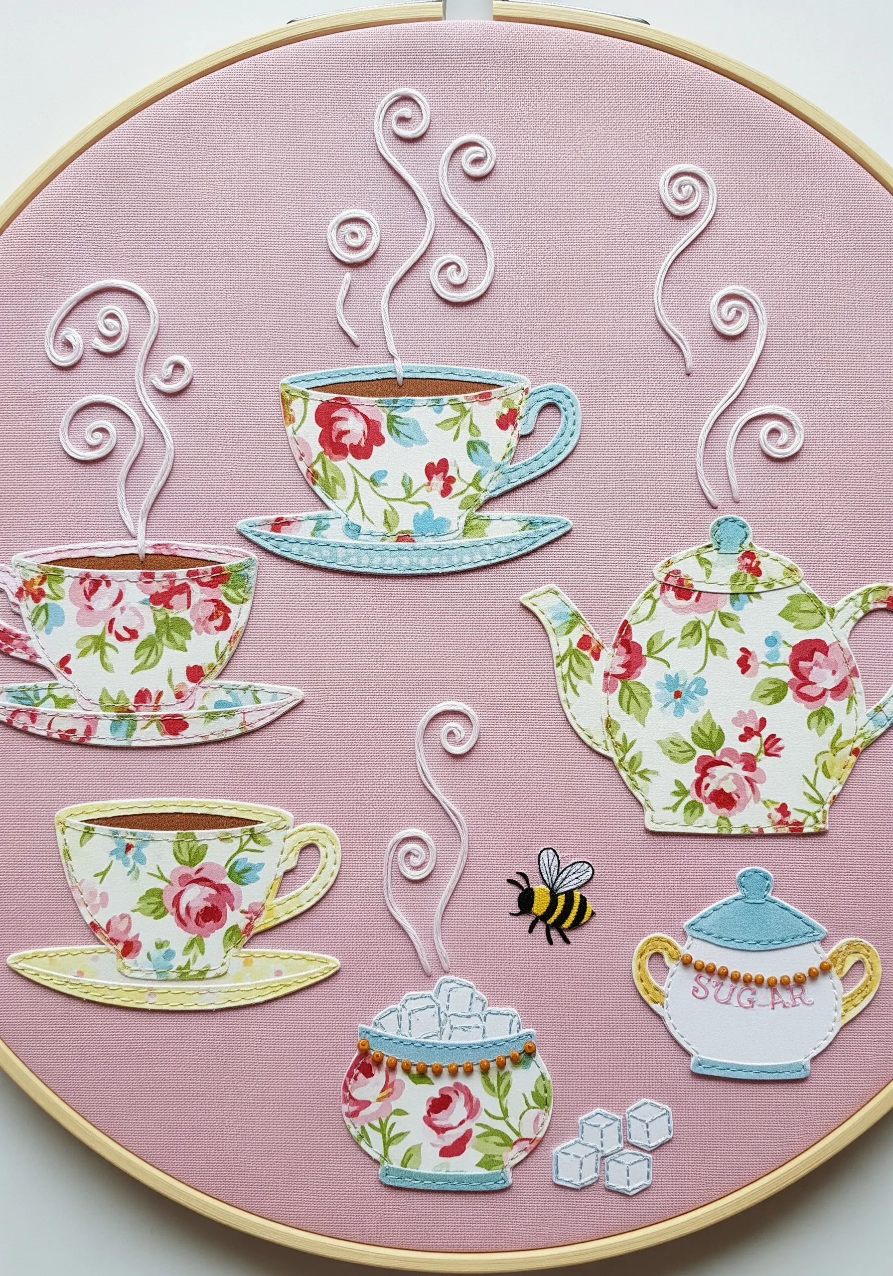 Hoop art of a tea party scene using floral fabric appliqué for the teacups and teapot.