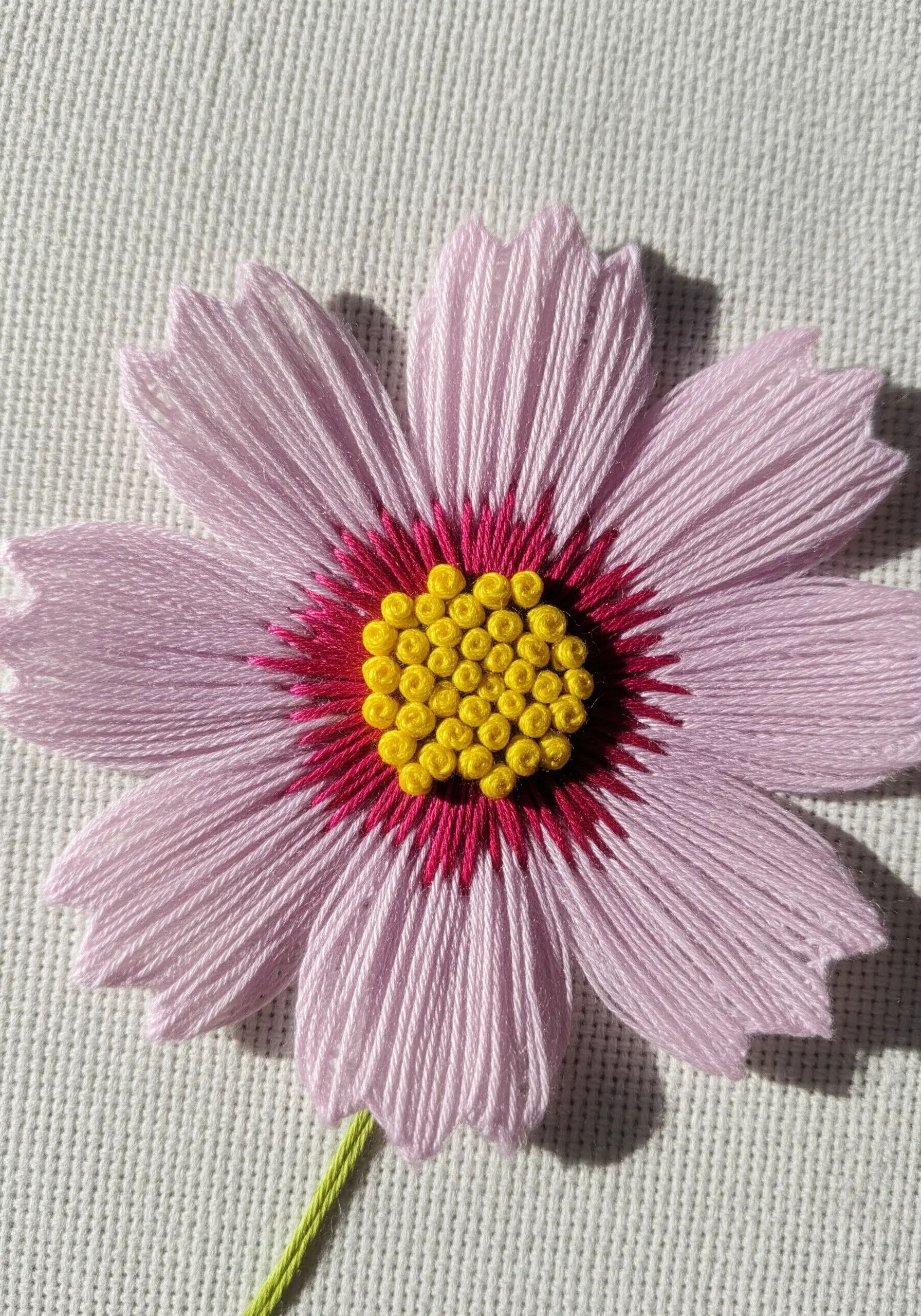 Pink cosmos flower embroidery with a textured yellow French knot center