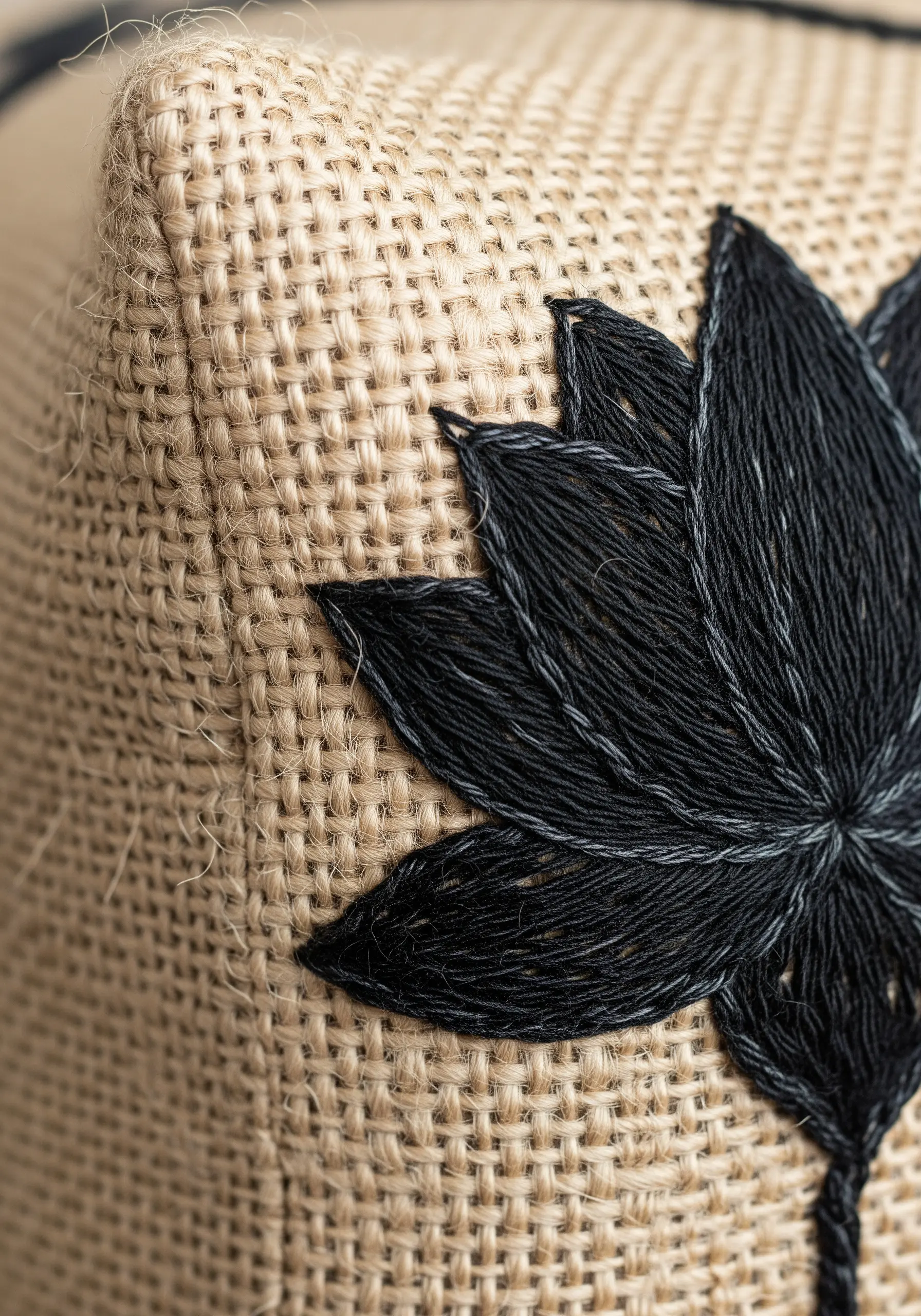 Black yarn flower embroidery detail on burlap fabric