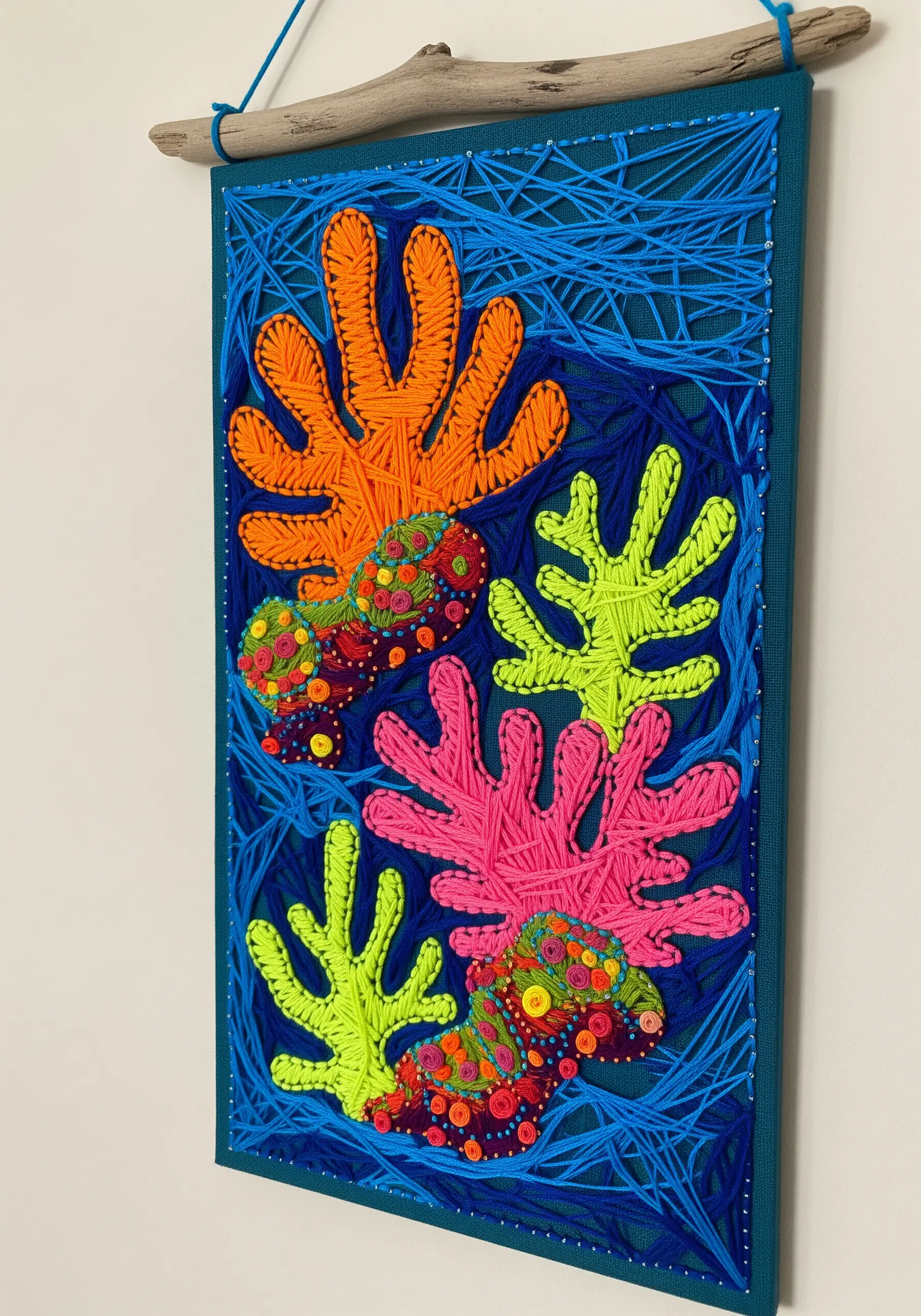 A vibrant, textured embroidery of a coral reef using yarn, beads, and various stitches.