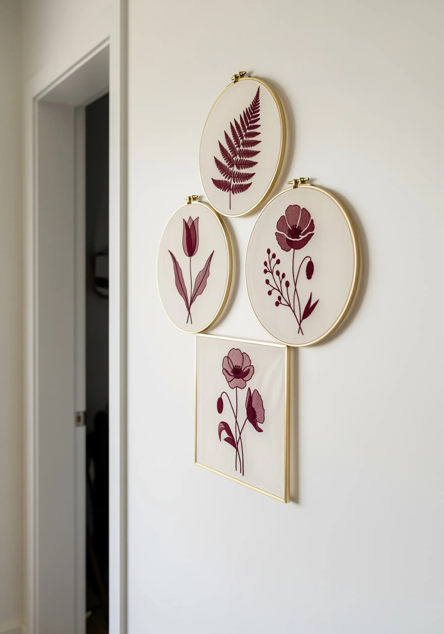 A cluster of four embroidery hoops and frames with different floral motifs in a cohesive color palette.