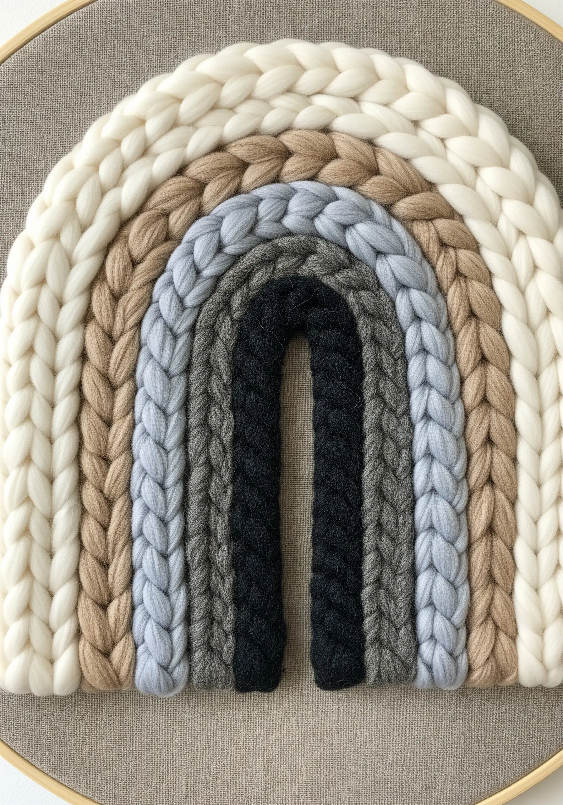 A close-up of a rainbow arch made from chunky braided yarn in neutral earth tones.