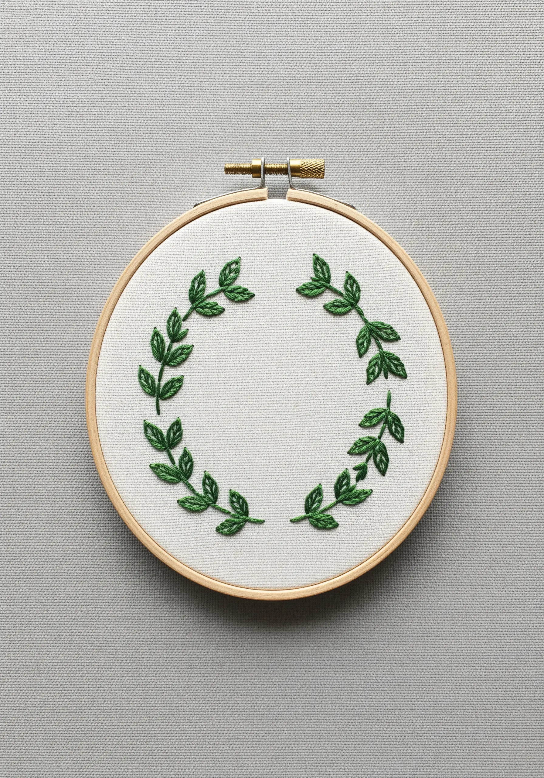 A minimalist green leaf wreath embroidered in a hoop, using fishbone stitch.