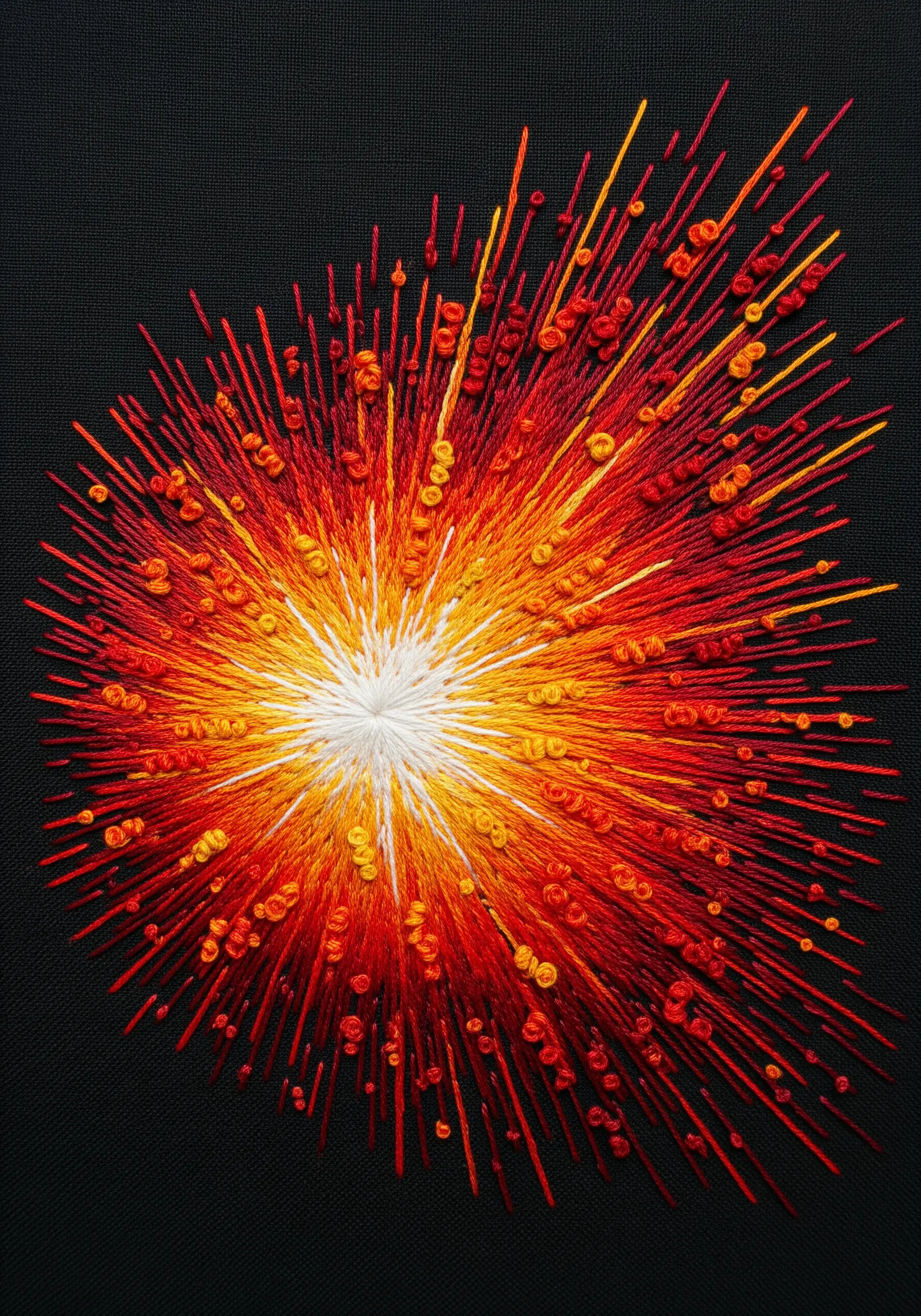 An embroidered explosion of stitches in a gradient from yellow to orange and red.