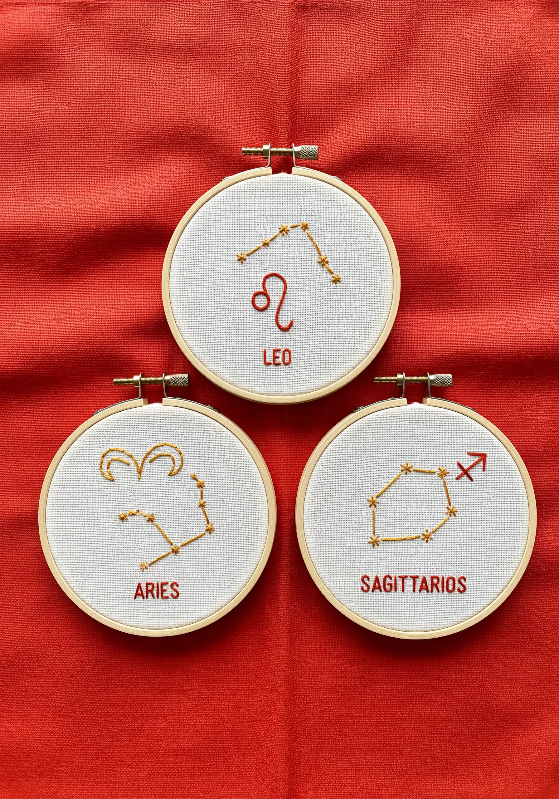A trio of small embroidery hoops featuring the fire signs: Leo, Aries, and Sagittarius.