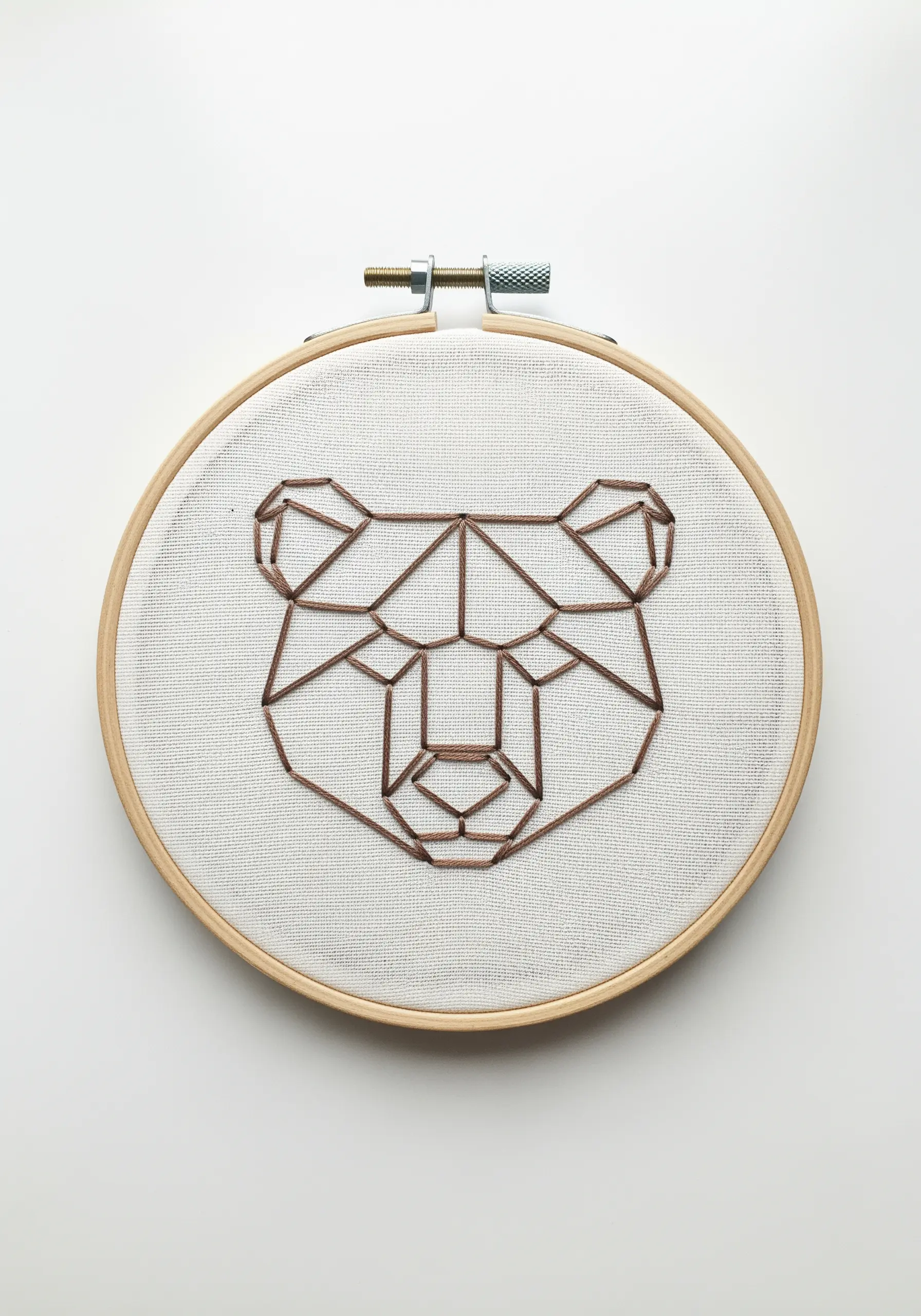 The outline of a bear's head embroidered with brown geometric lines.