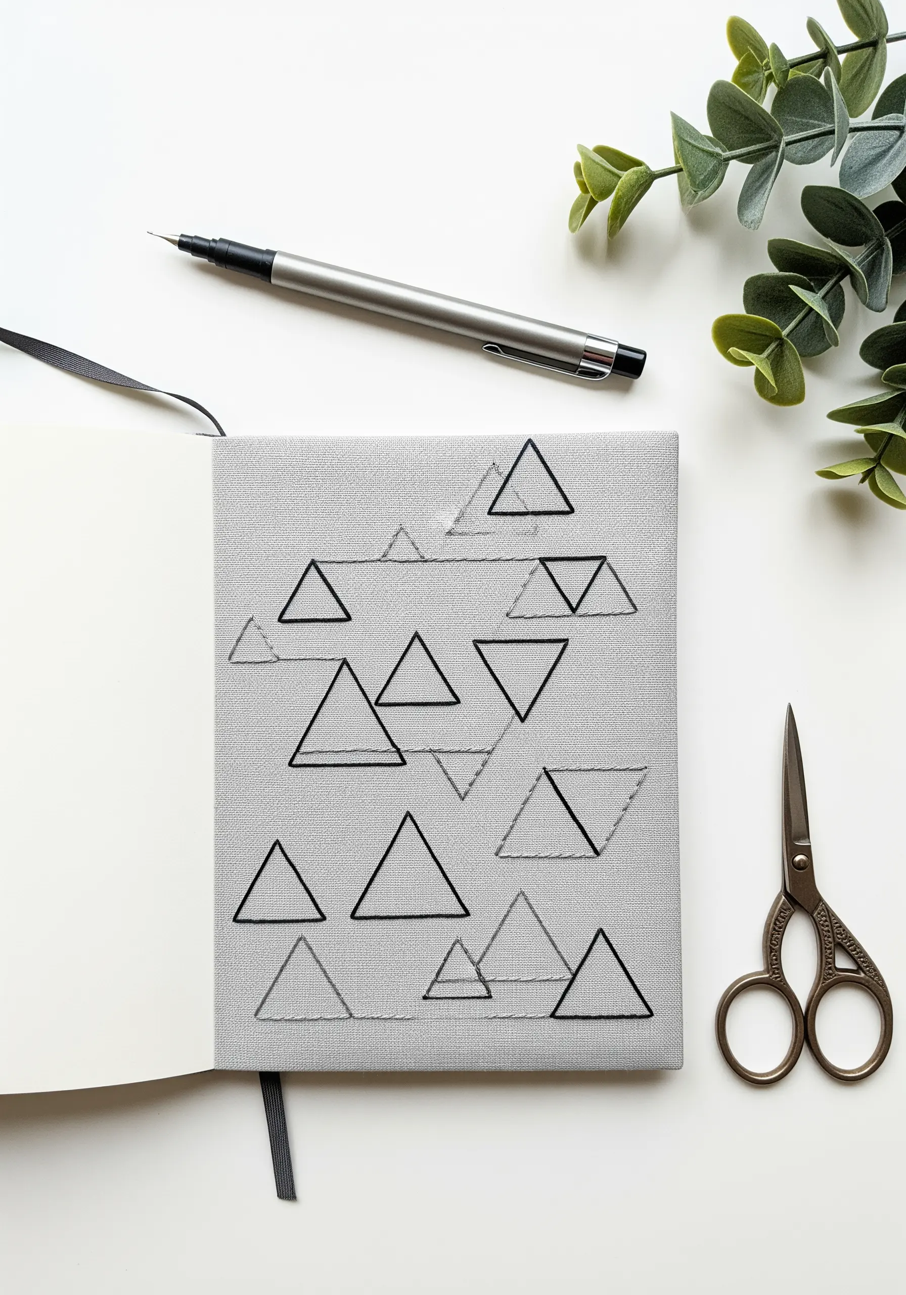 A pattern of geometric triangles in black and gray thread on a gray journal cover.