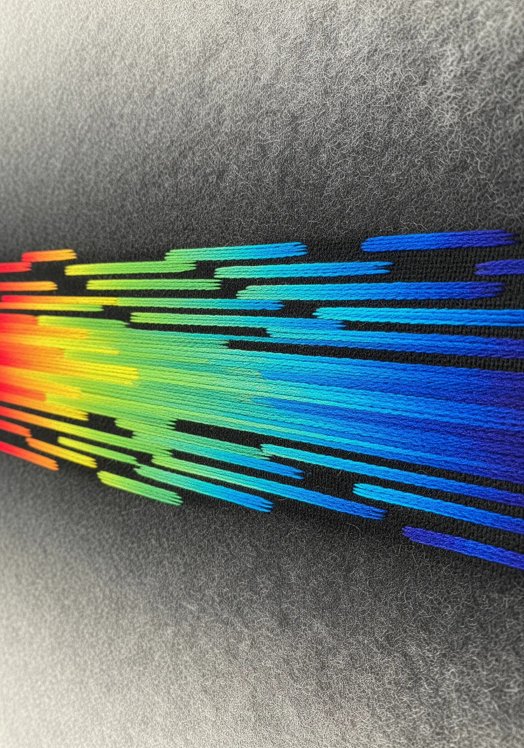 A close-up of a vibrant rainbow gradient with a staggered, 'glitchy' stitch effect.