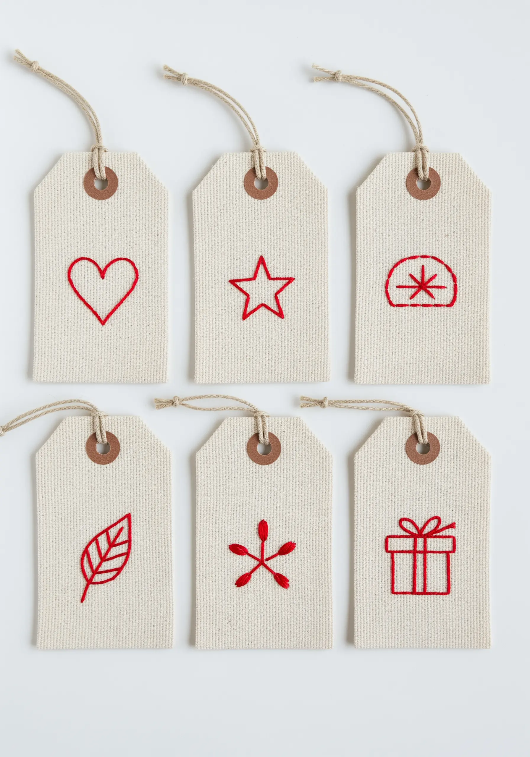 A set of six canvas gift tags, each with a simple red embroidered icon.