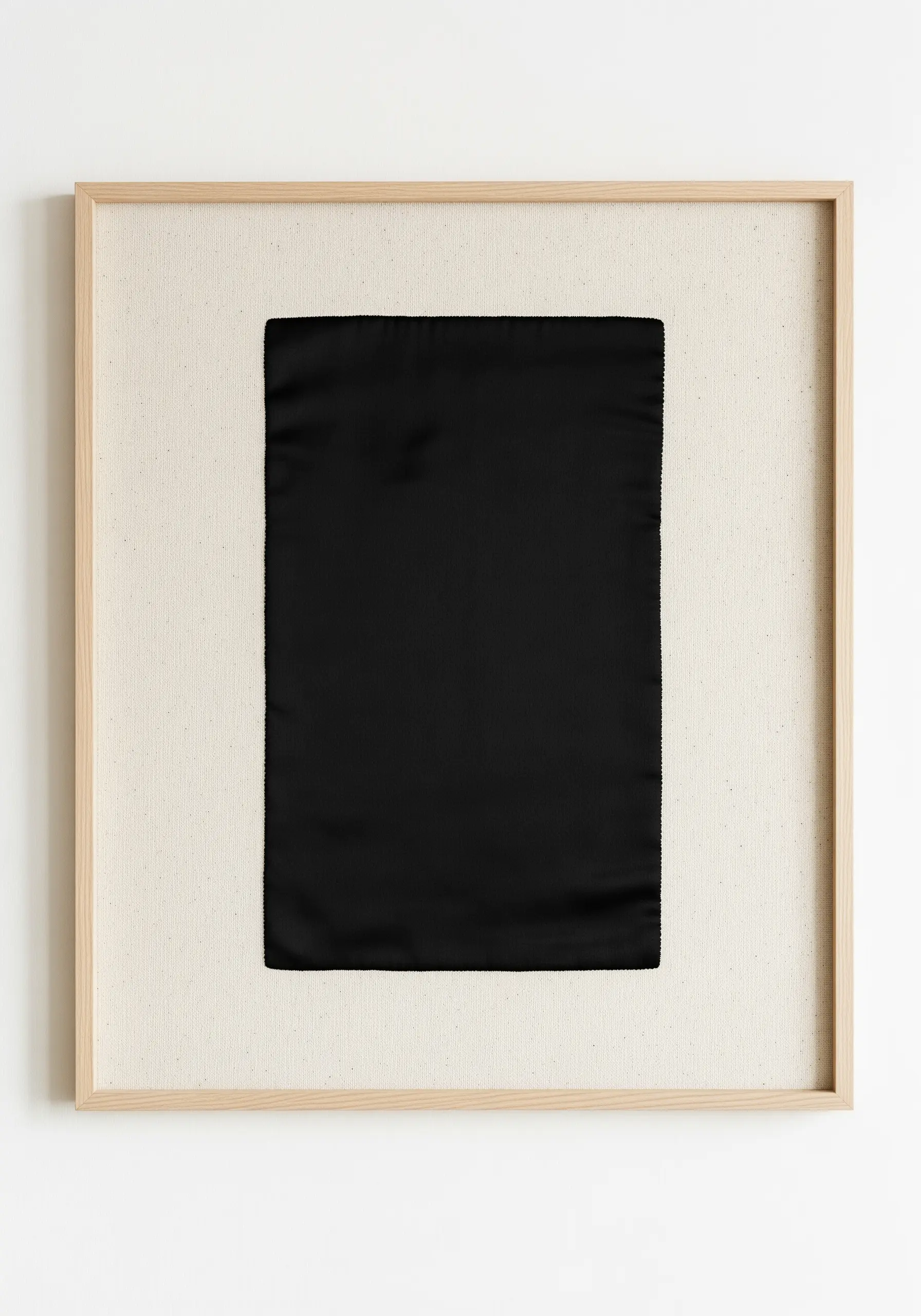 A perfectly executed solid black satin stitch rectangle framed on neutral fabric.