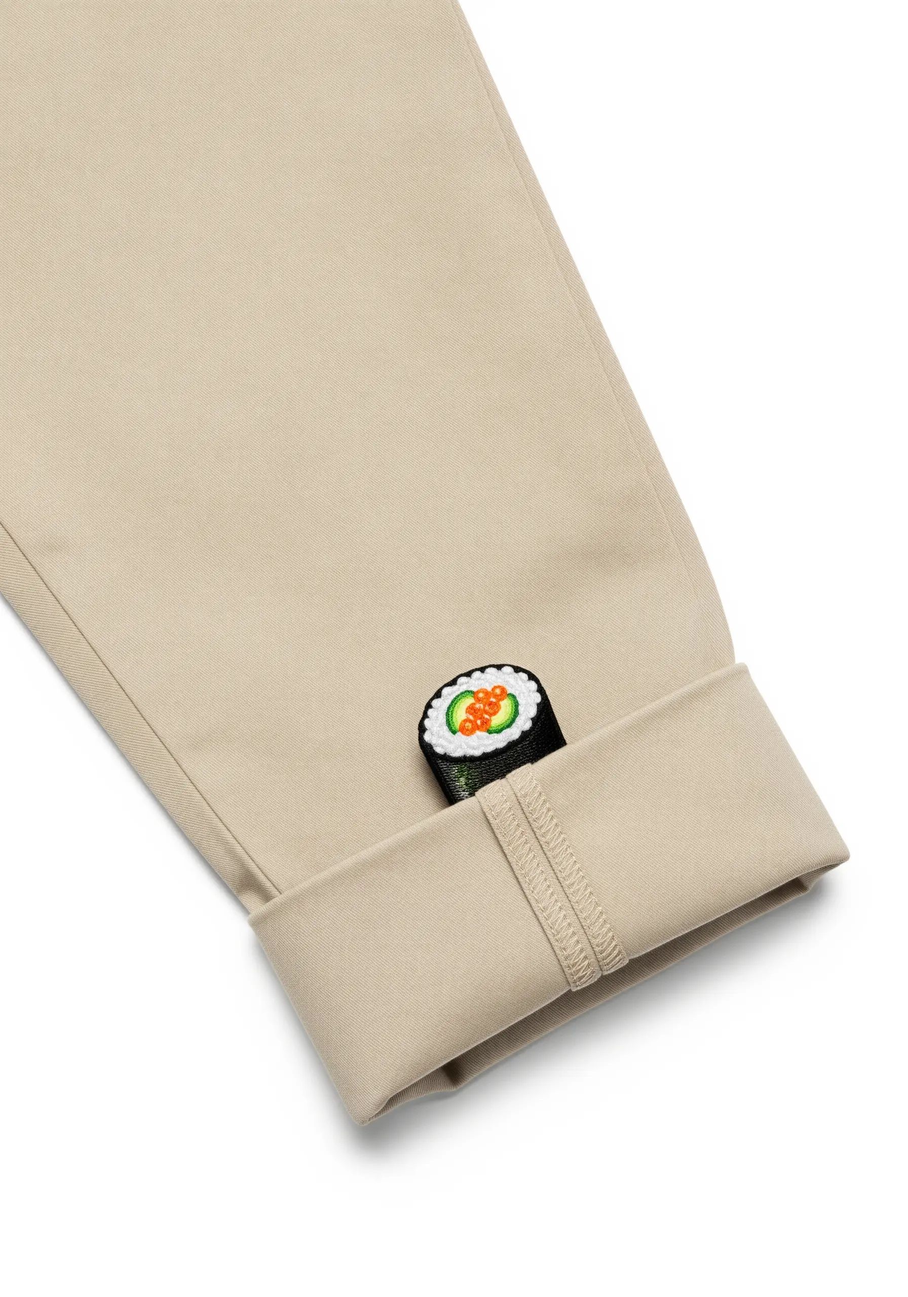 A small, embroidered sushi roll peeking out from a rolled-up pant cuff.