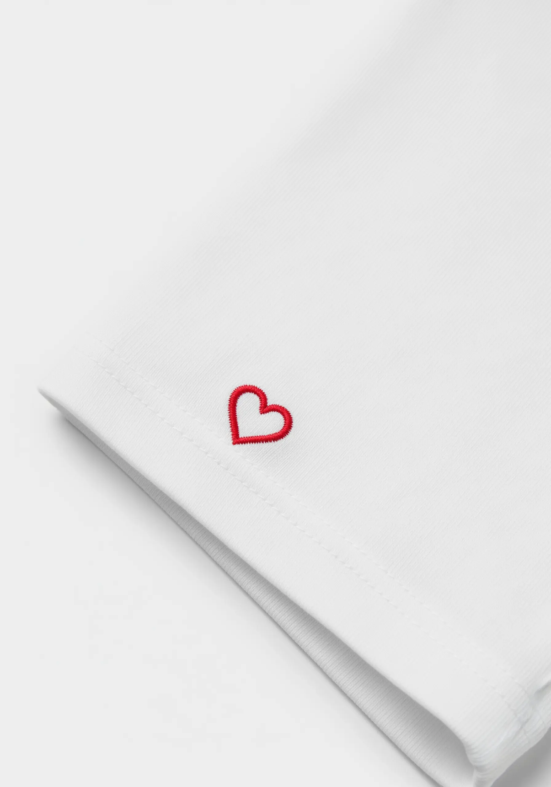A tiny, perfectly formed red heart embroidered on a sleeve hem.