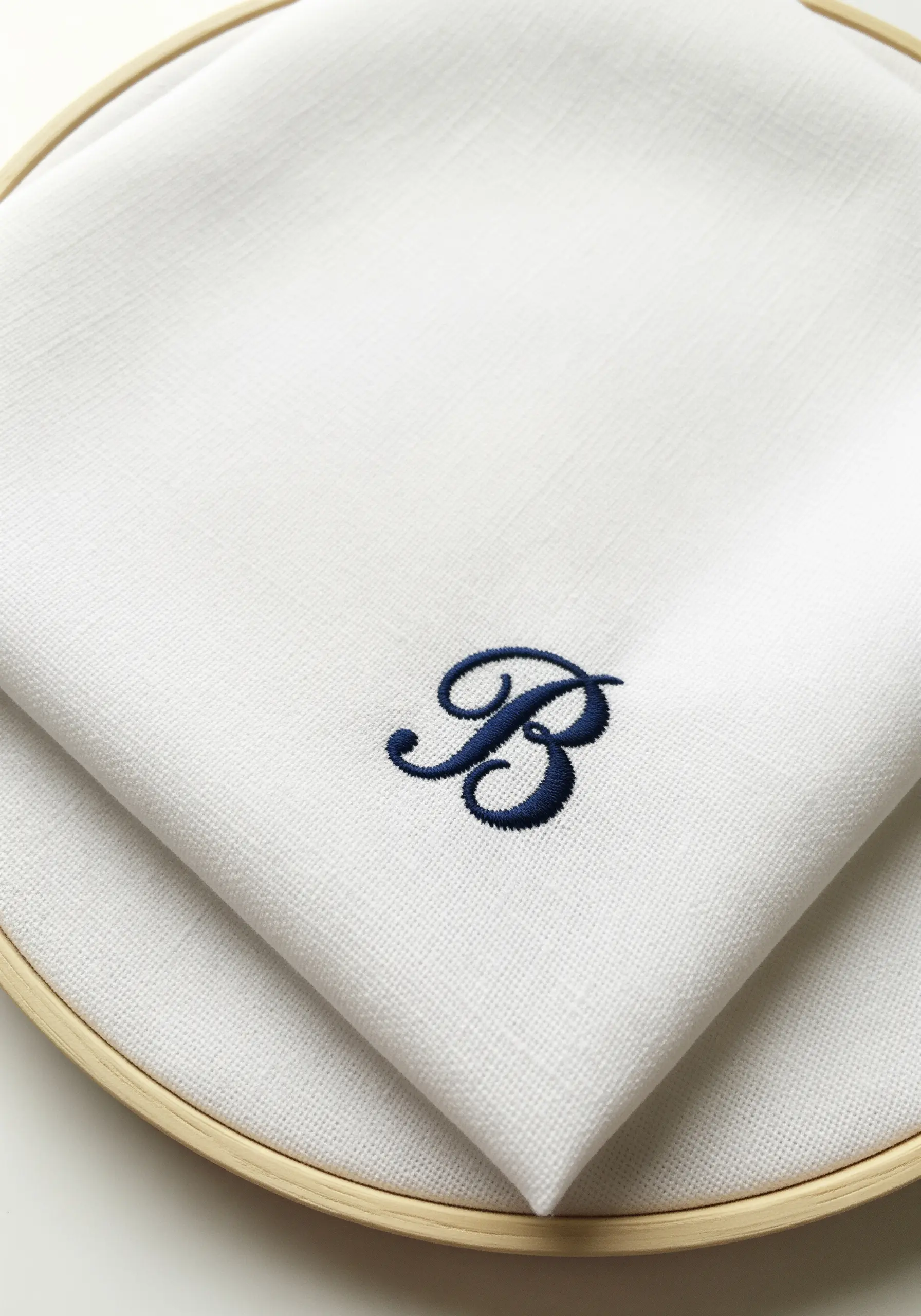 A classic navy blue satin-stitched 'B' monogram on crisp white linen.