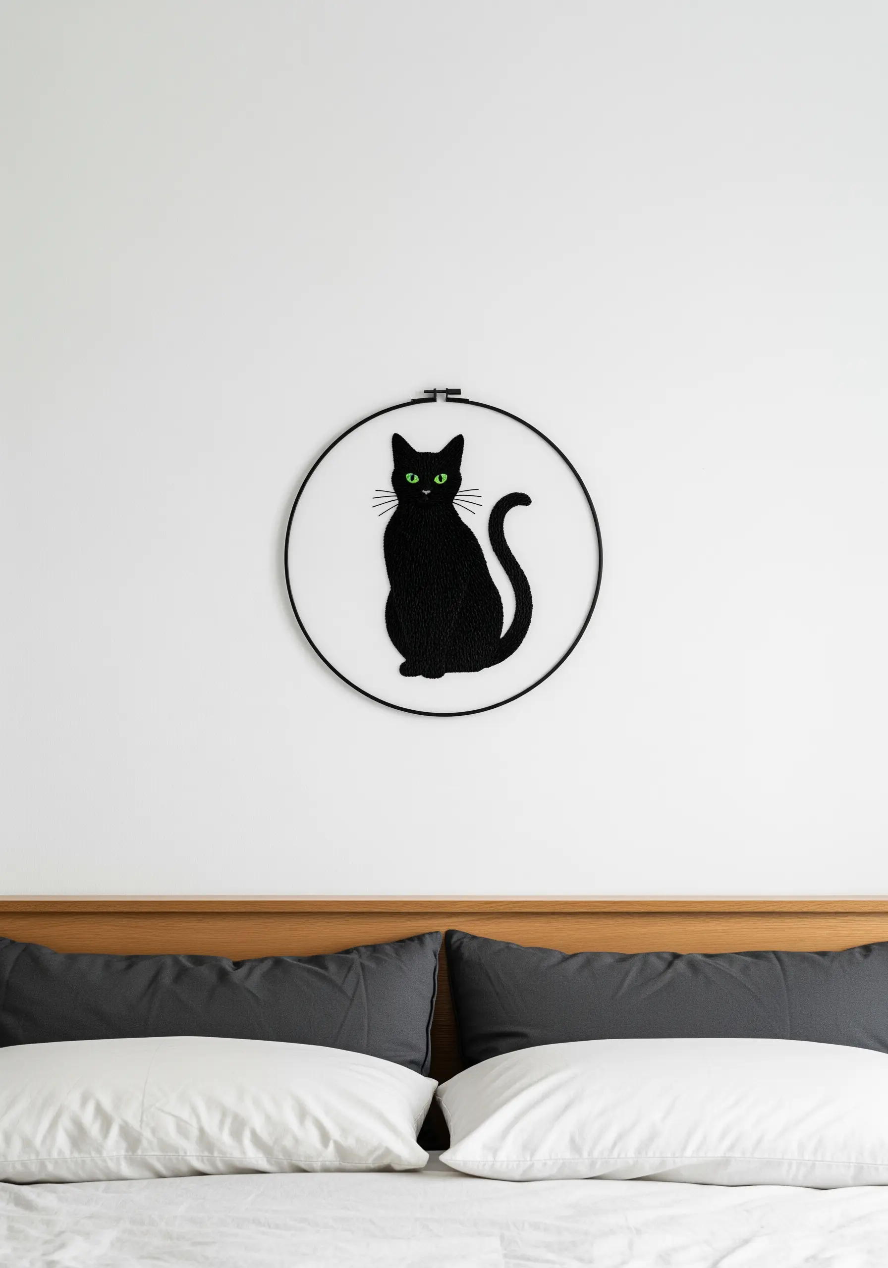 Black cat silhouette embroidered with striking green eyes in a black hoop.