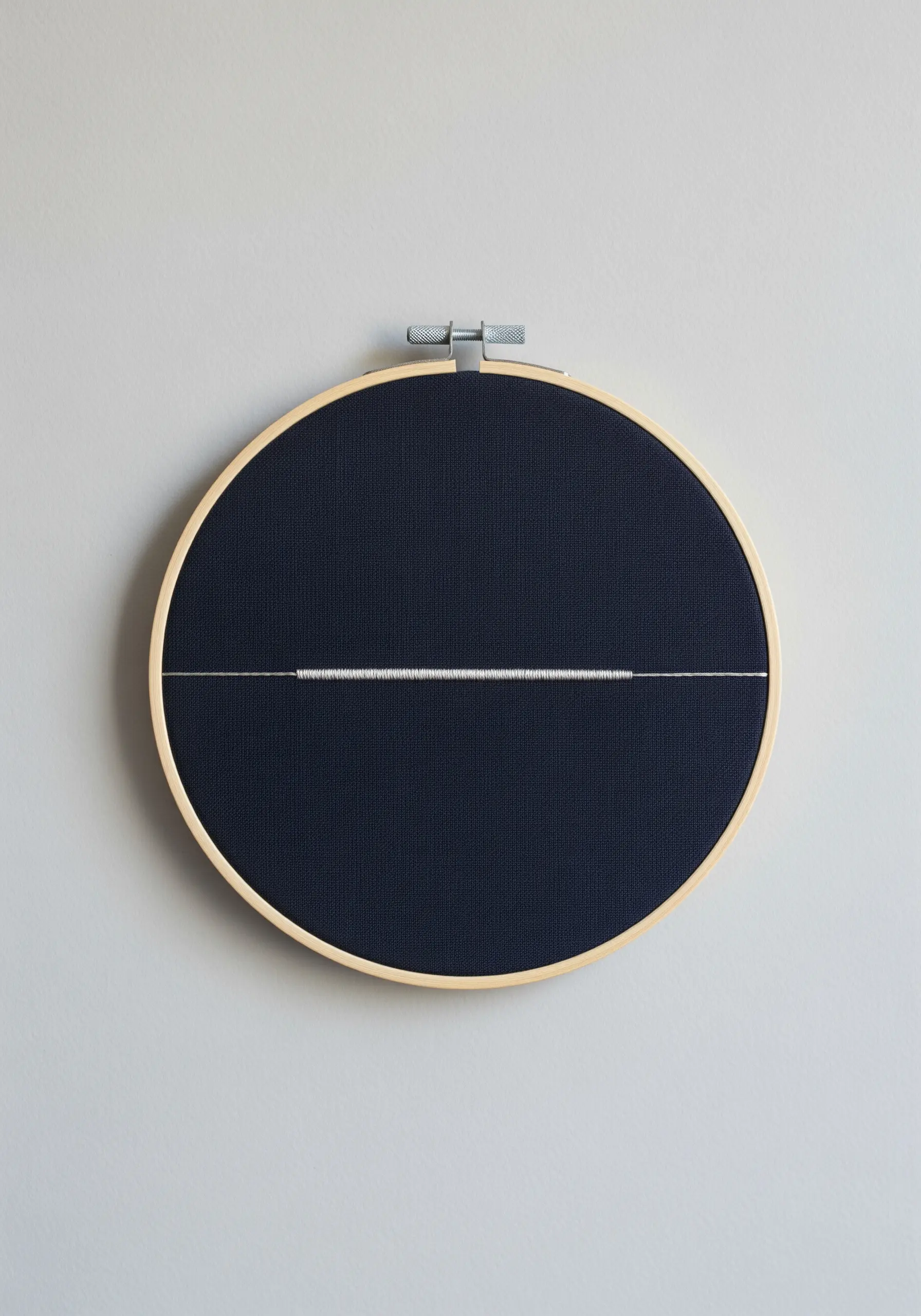 A single, fine white line of stitches across the center of a dark navy hoop.
