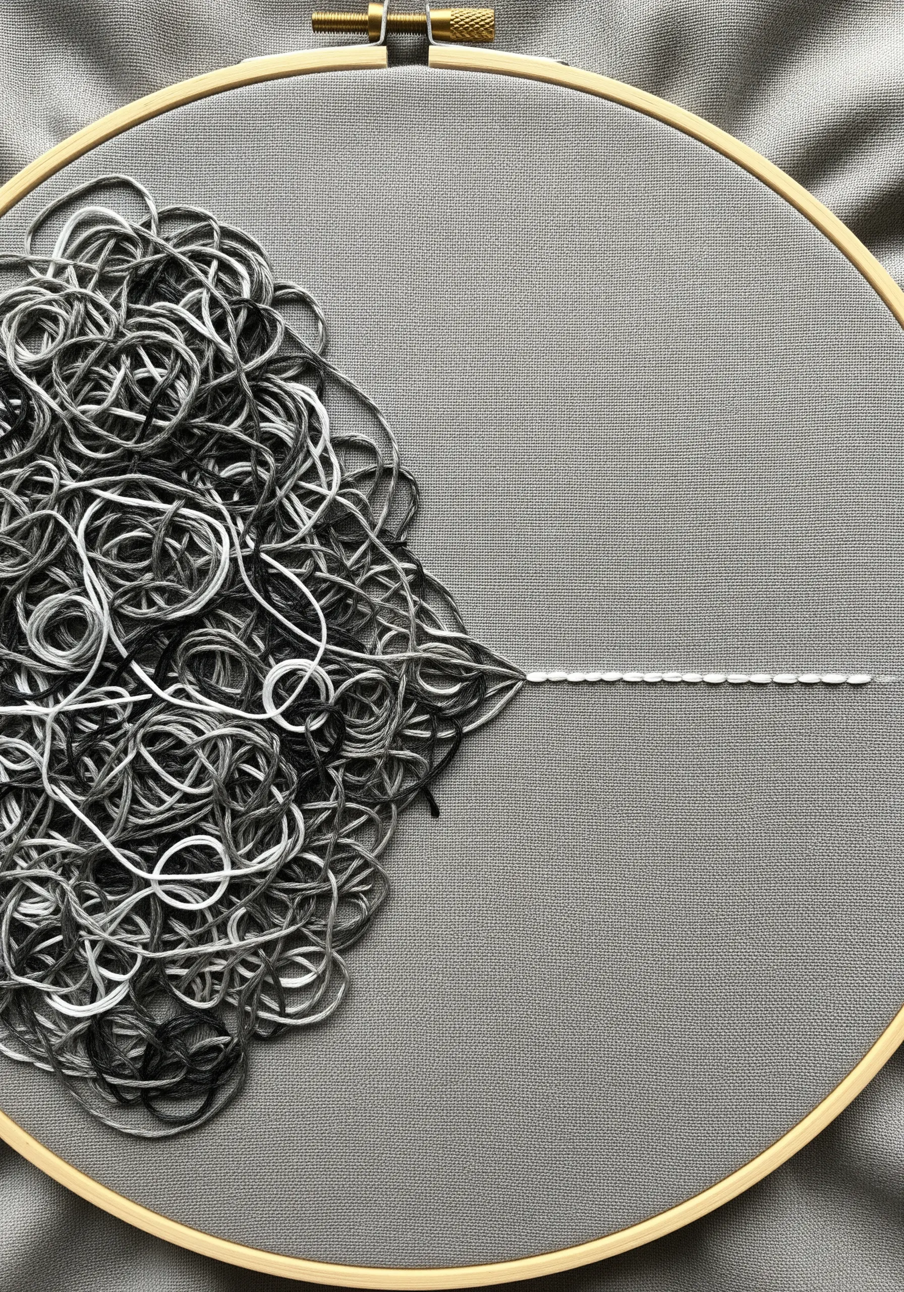 A mass of tangled grey and white threads resolves into a single, neat stitched line.
