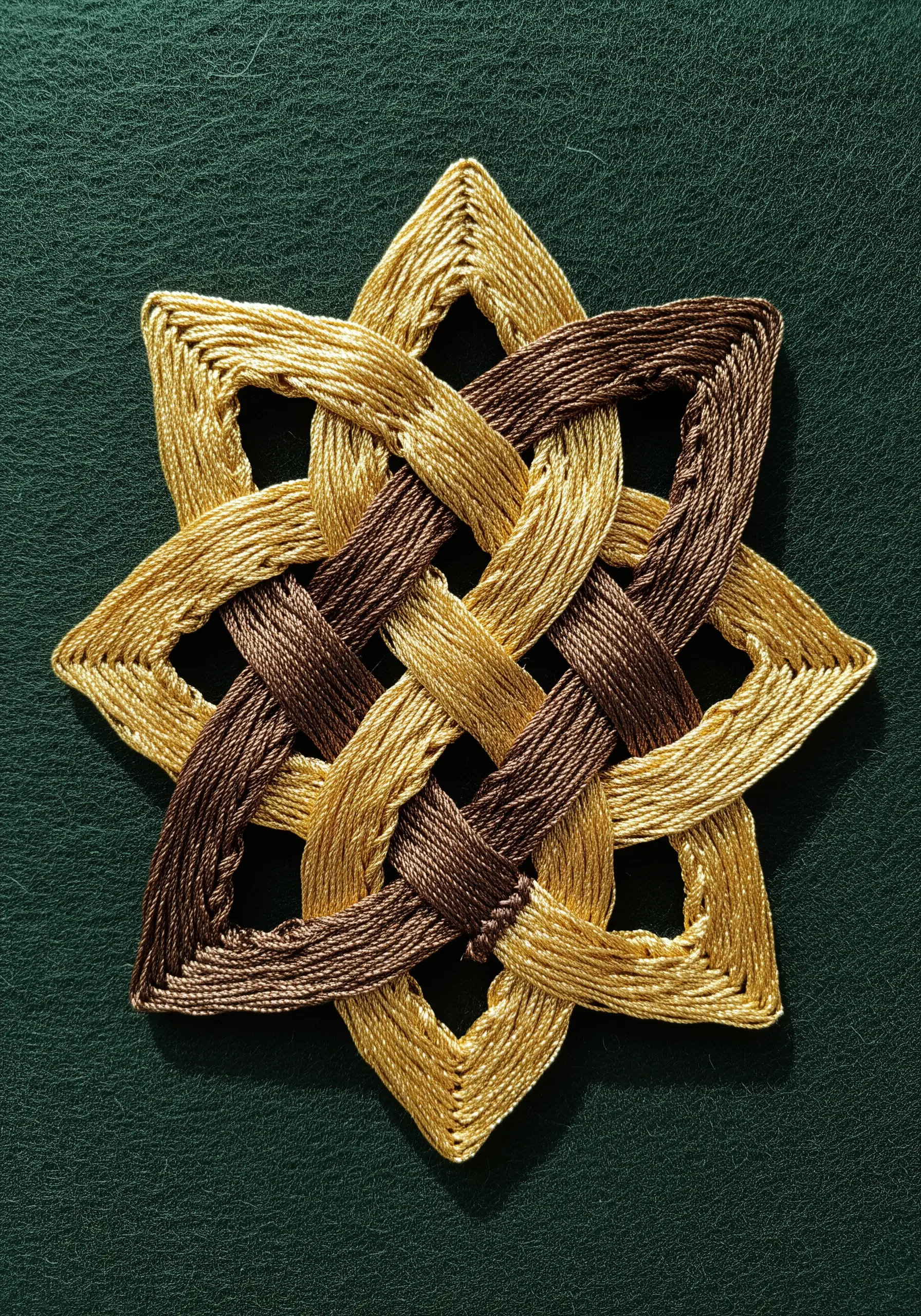 An interwoven Celtic knot in brown and gold thread with precise satin stitches.