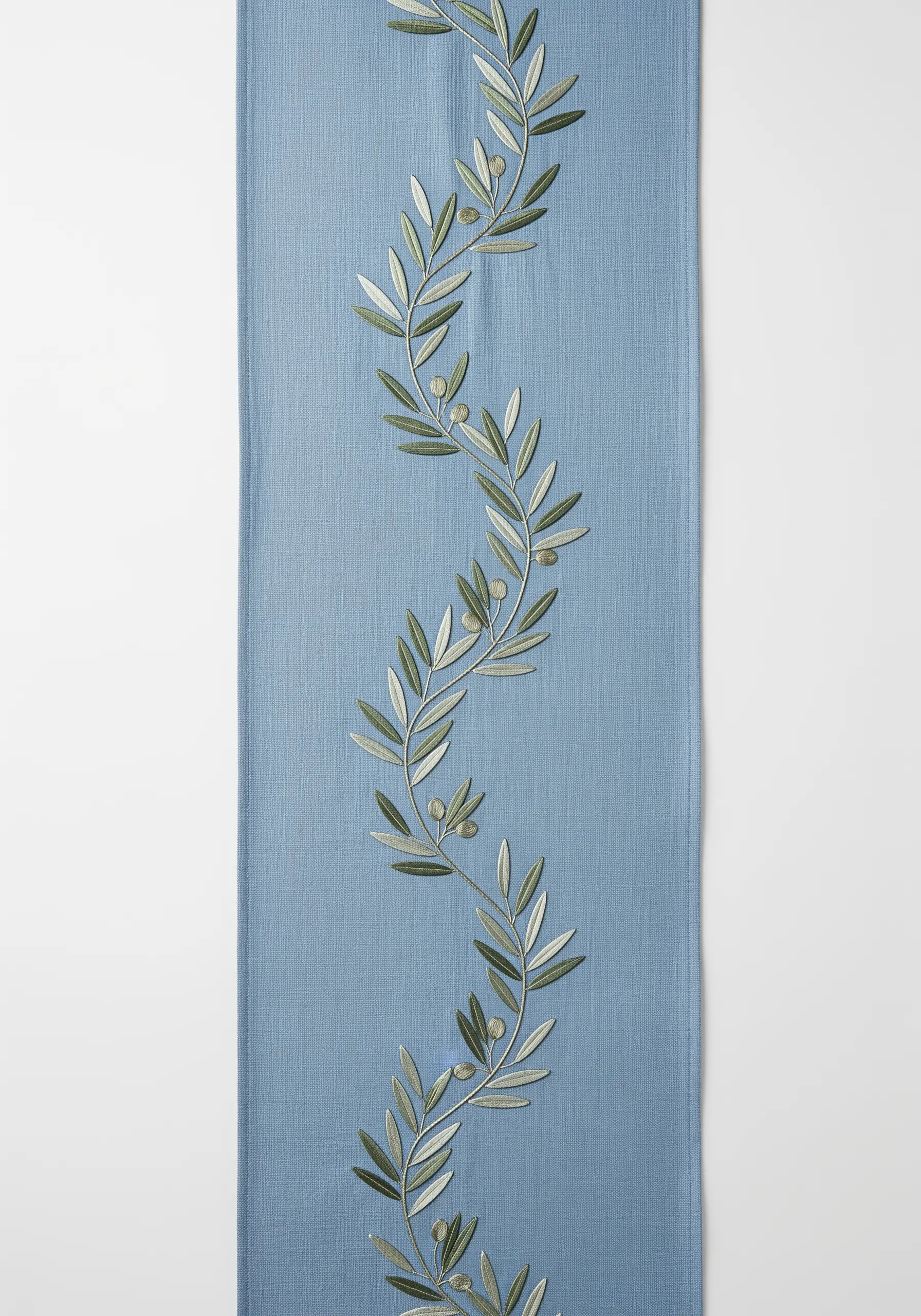 A meandering olive branch embroidered in soft, tonal greens on a blue table runner.