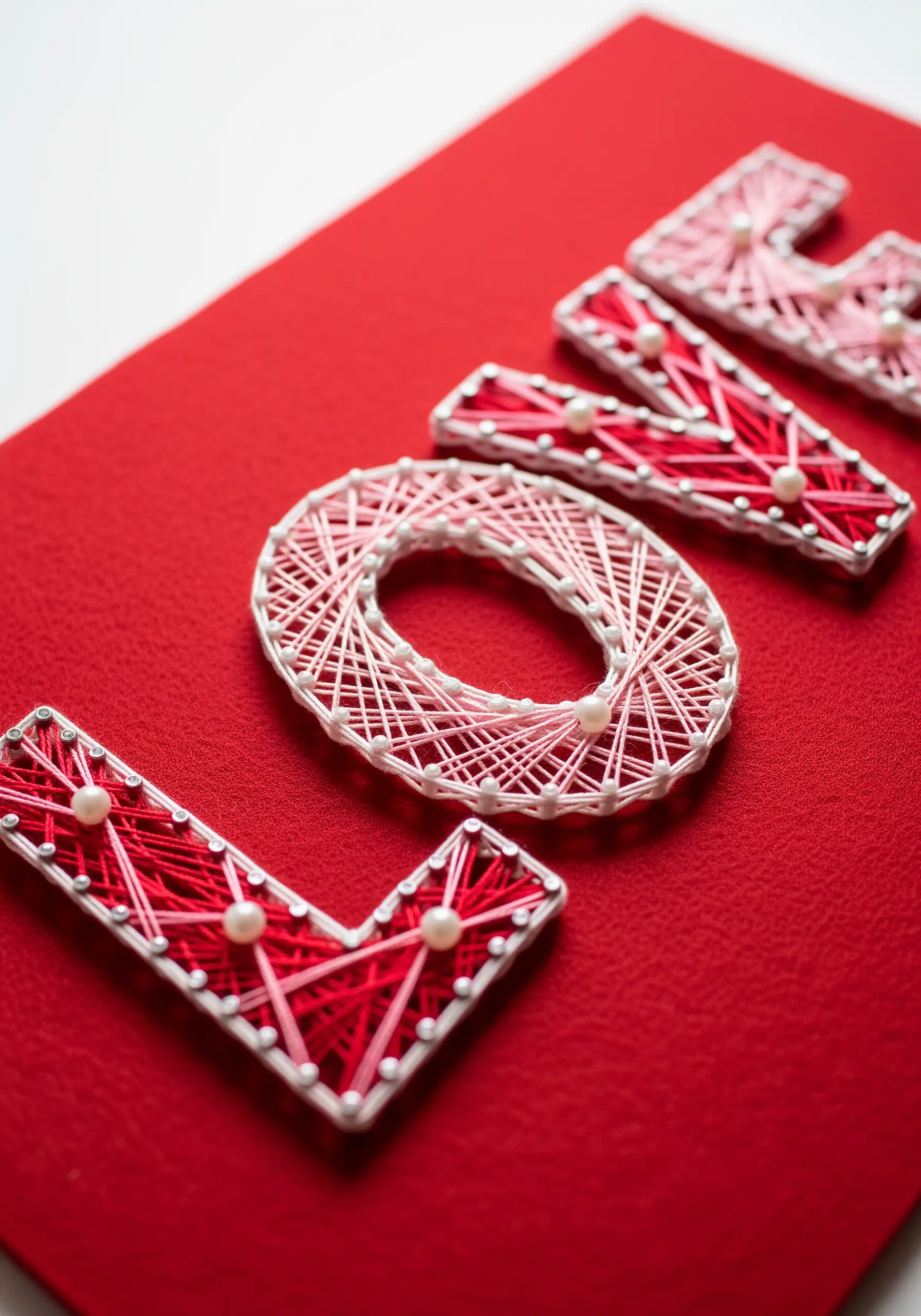 Red string art saying LOVE on a red felt background
