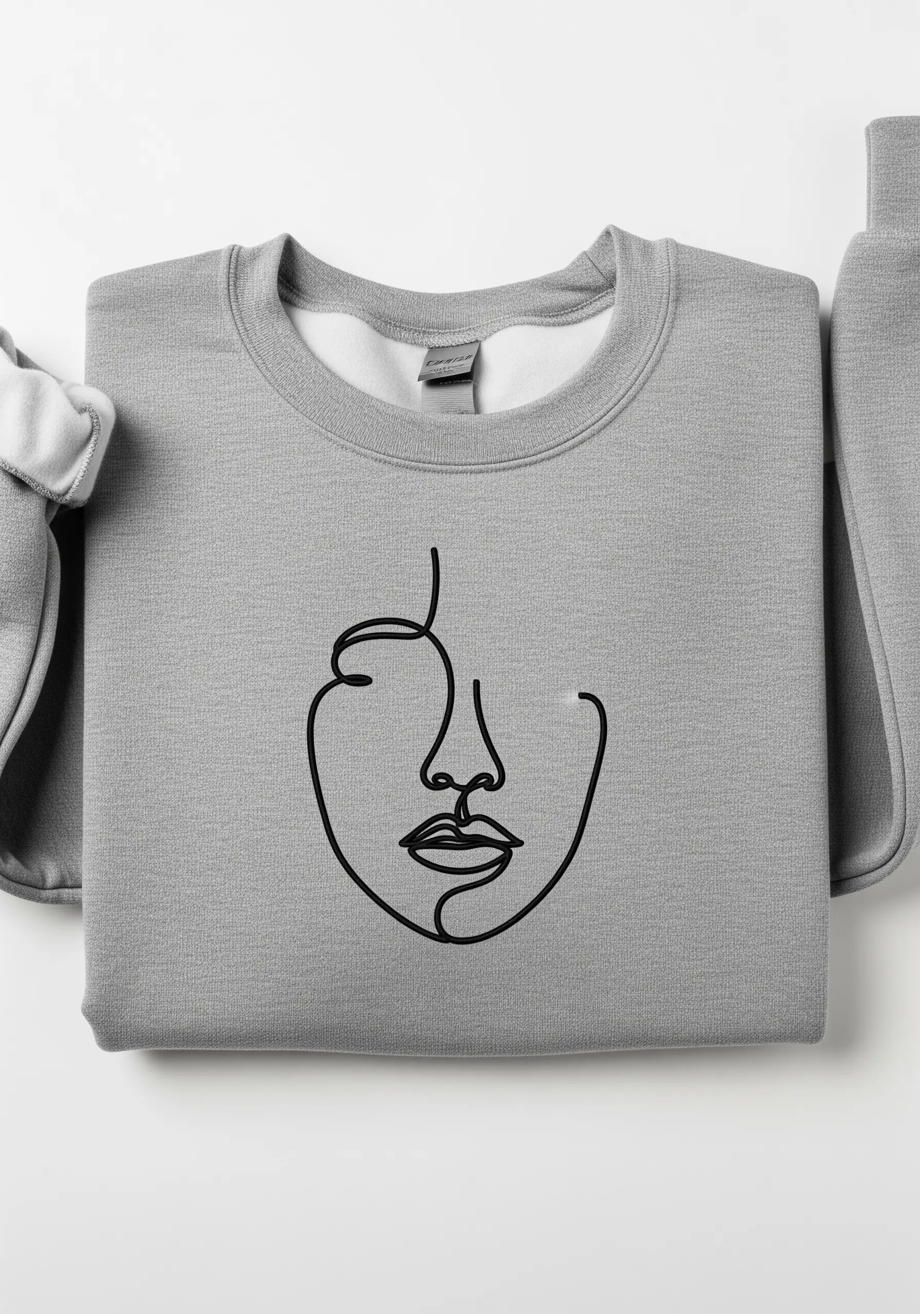 A minimal, single-line abstract face embroidered in black on a gray sweatshirt.