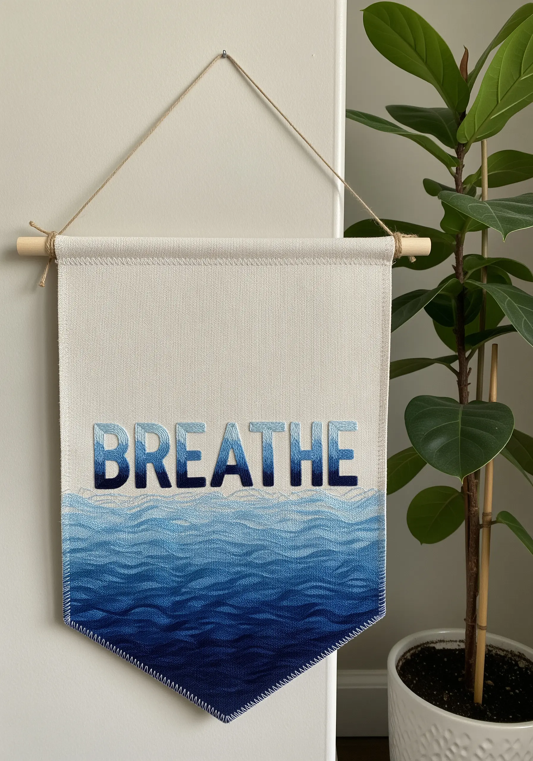 Wall banner hanging with the word BREATHE above blue ombre ocean wave stitching
