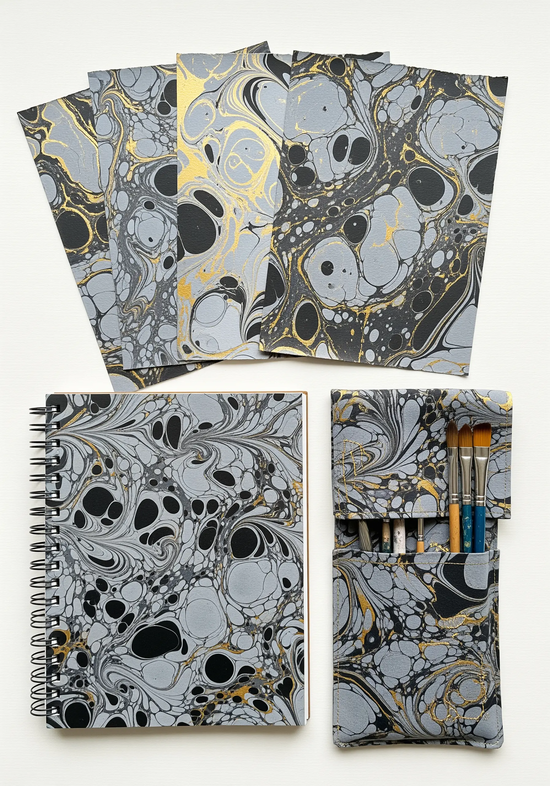 An embroidered pencil case and notebook covered in the same gray and gold marbled paper.