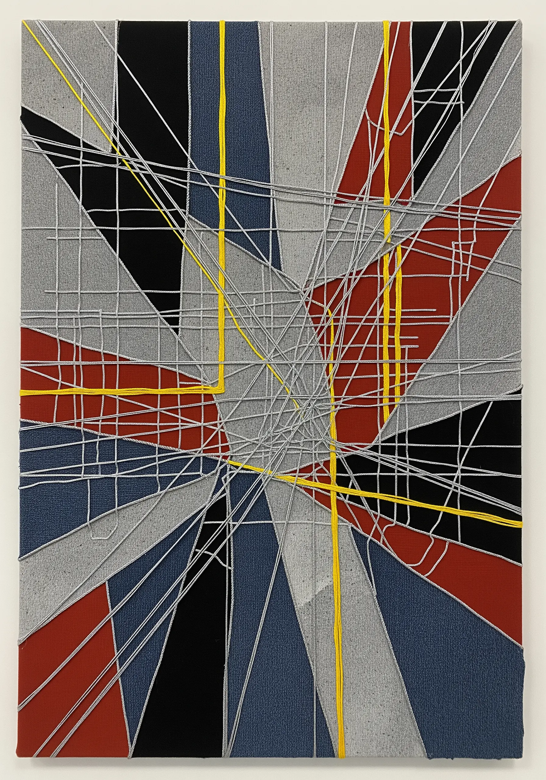 Geometric fabric collage in gray, black, and red with a grid of white and yellow stitches.