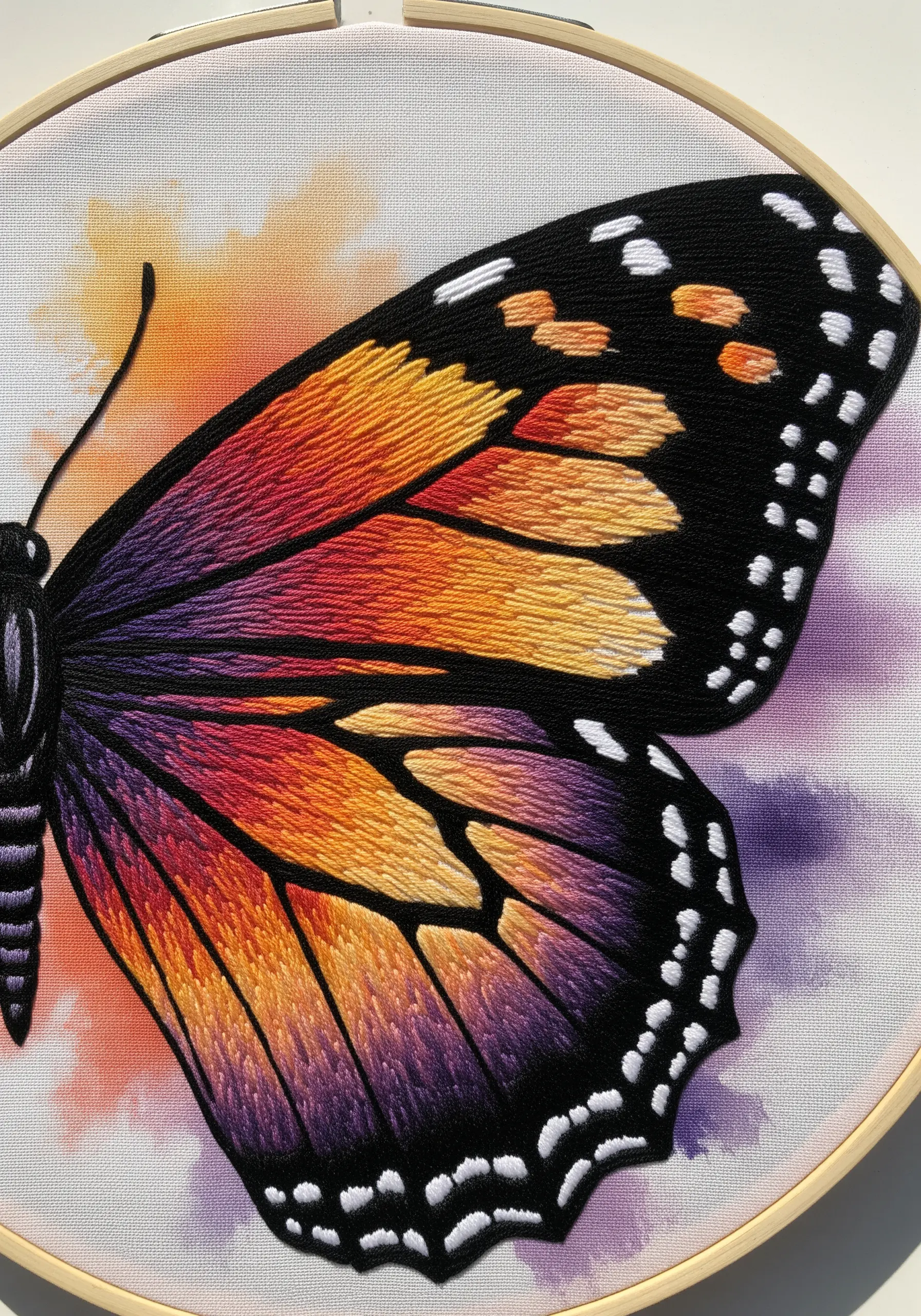 Close-up of an embroidered butterfly wing with a watercolor background that matches the thread colors.