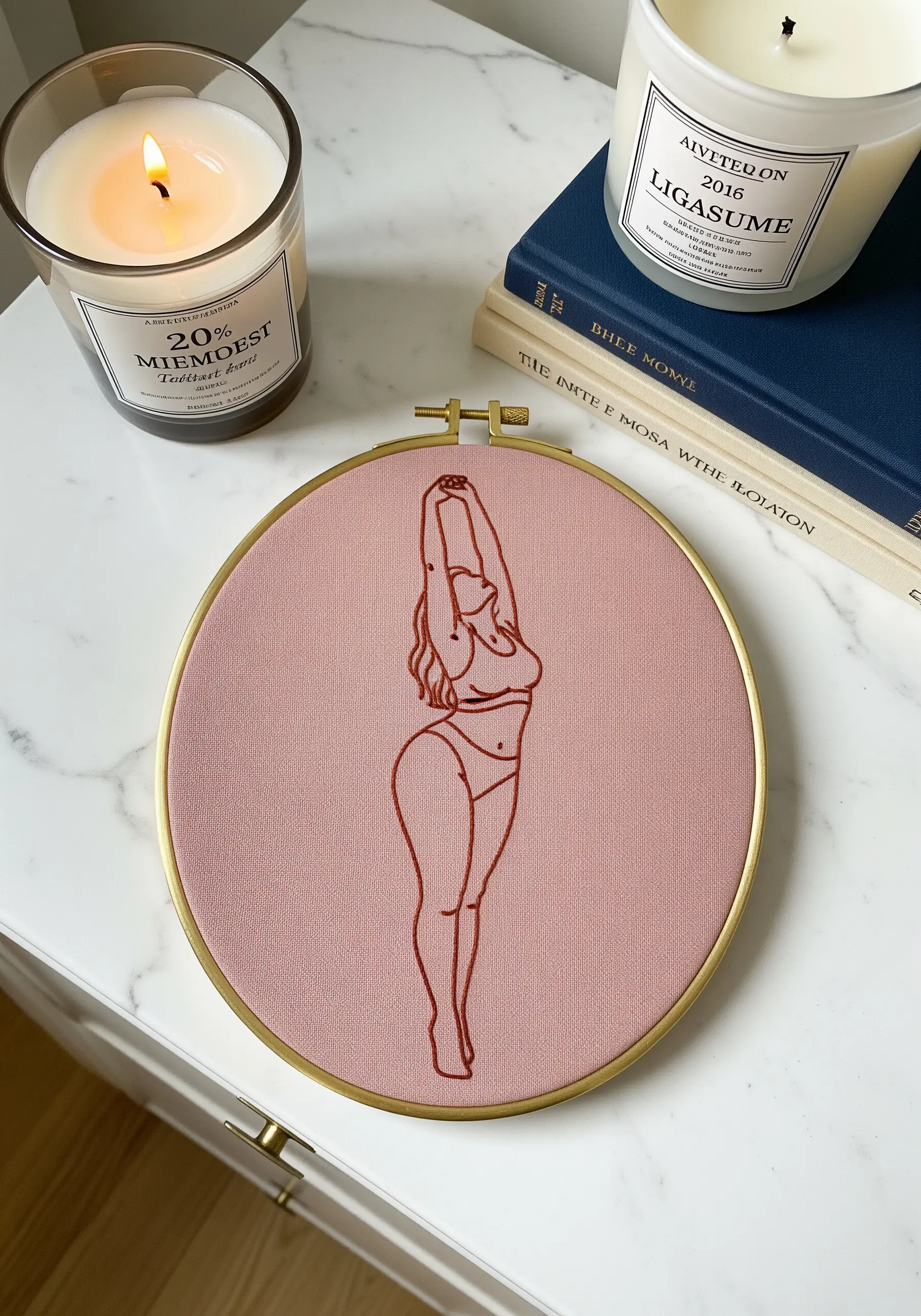 Line art of a stretching female figure stitched in terracotta thread on dusty rose fabric.