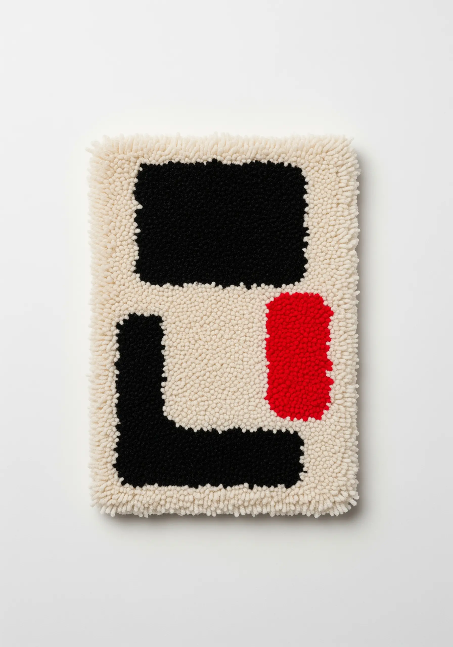 Abstract punch needle piece with bold black and red shapes on a cream, un-punched background.