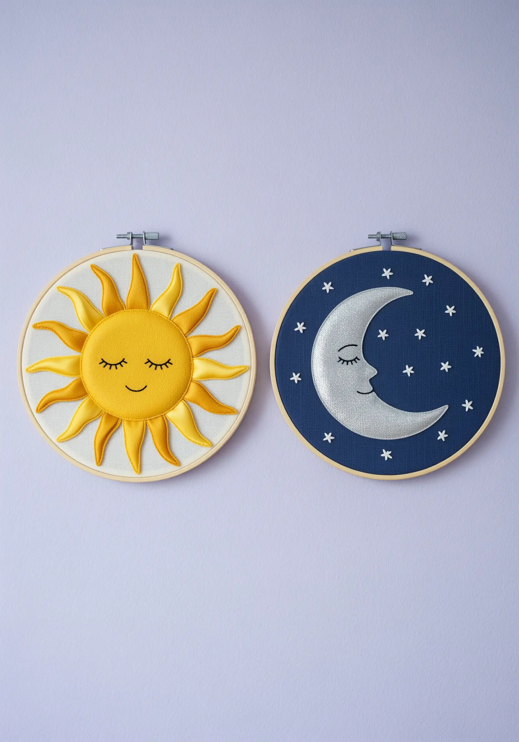 Two embroidery hoops, one with a satin ribbon sun and one with a silver appliqué moon.