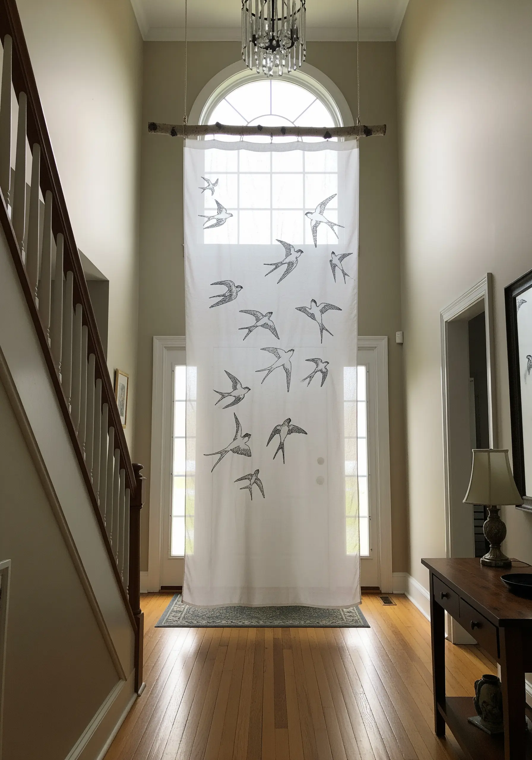 Sheer white curtain with black thread embroidery of flying swallows.
