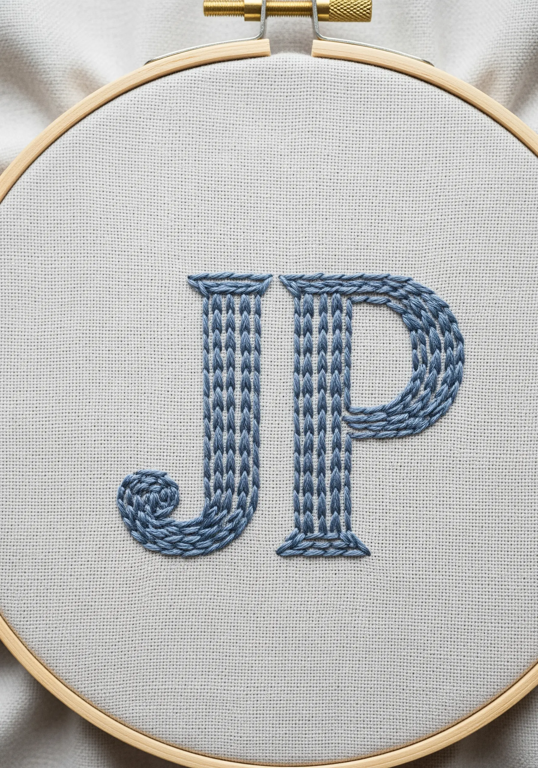 Initials 'JP' filled with a textured, slanted satin stitch in blue.
