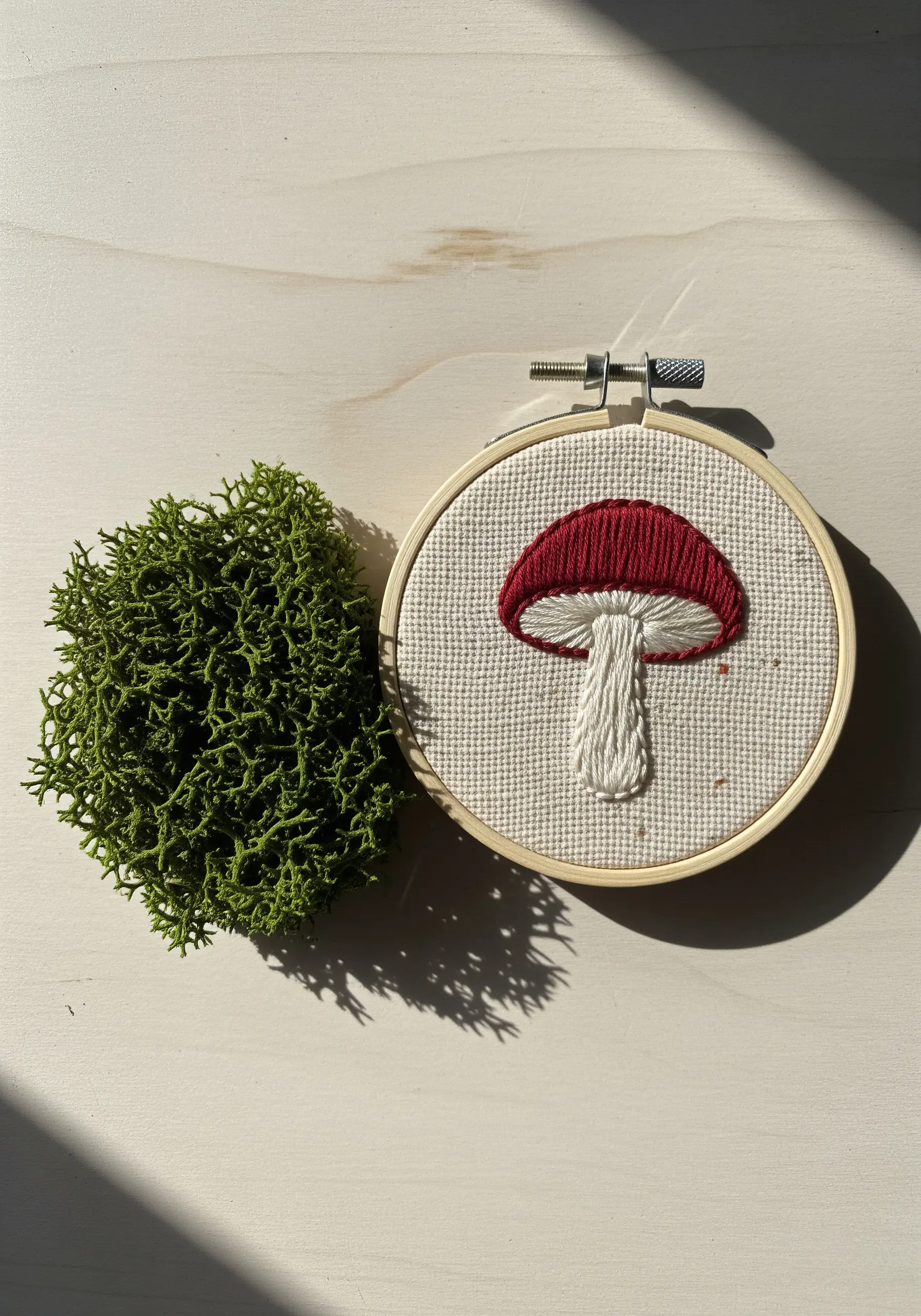 A small red and white mushroom embroidered with satin stitch.