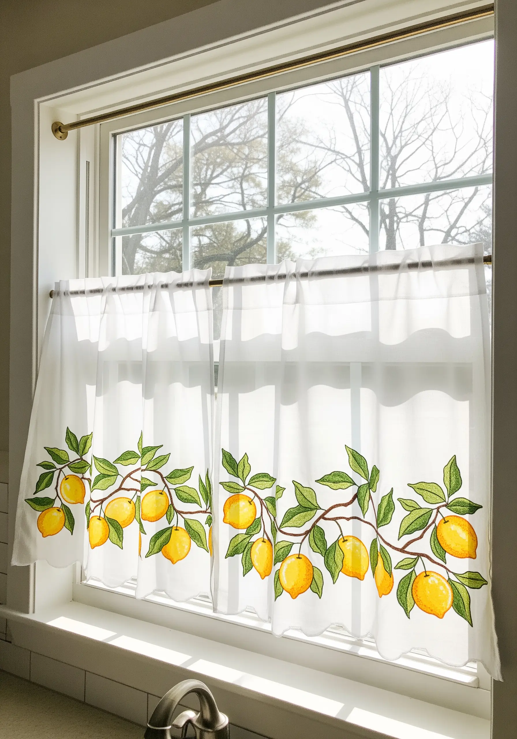 A border of bright yellow lemons and green leaves on white café curtains.