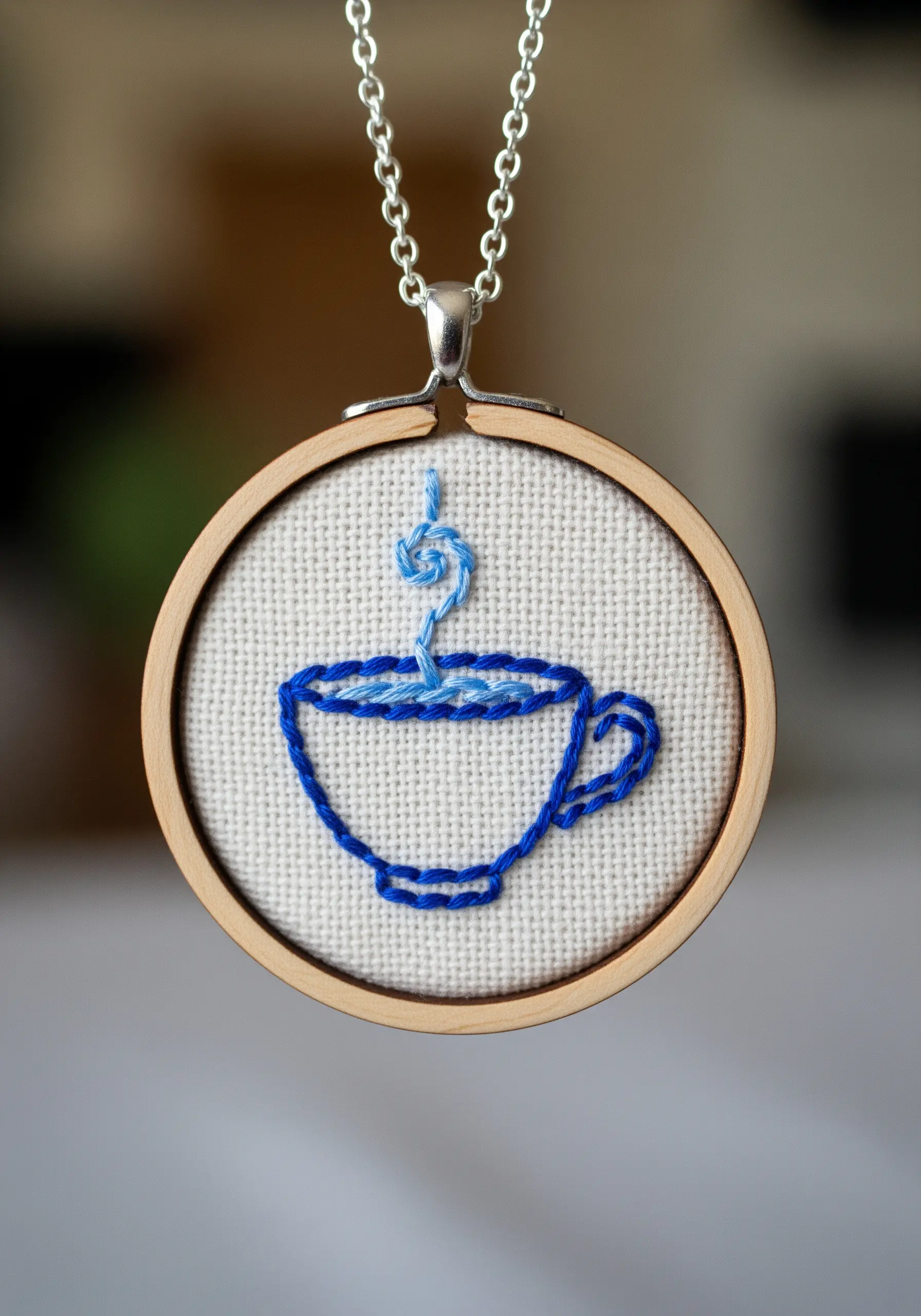 A simple outline of a coffee cup with variegated blue thread for the steam and liquid.