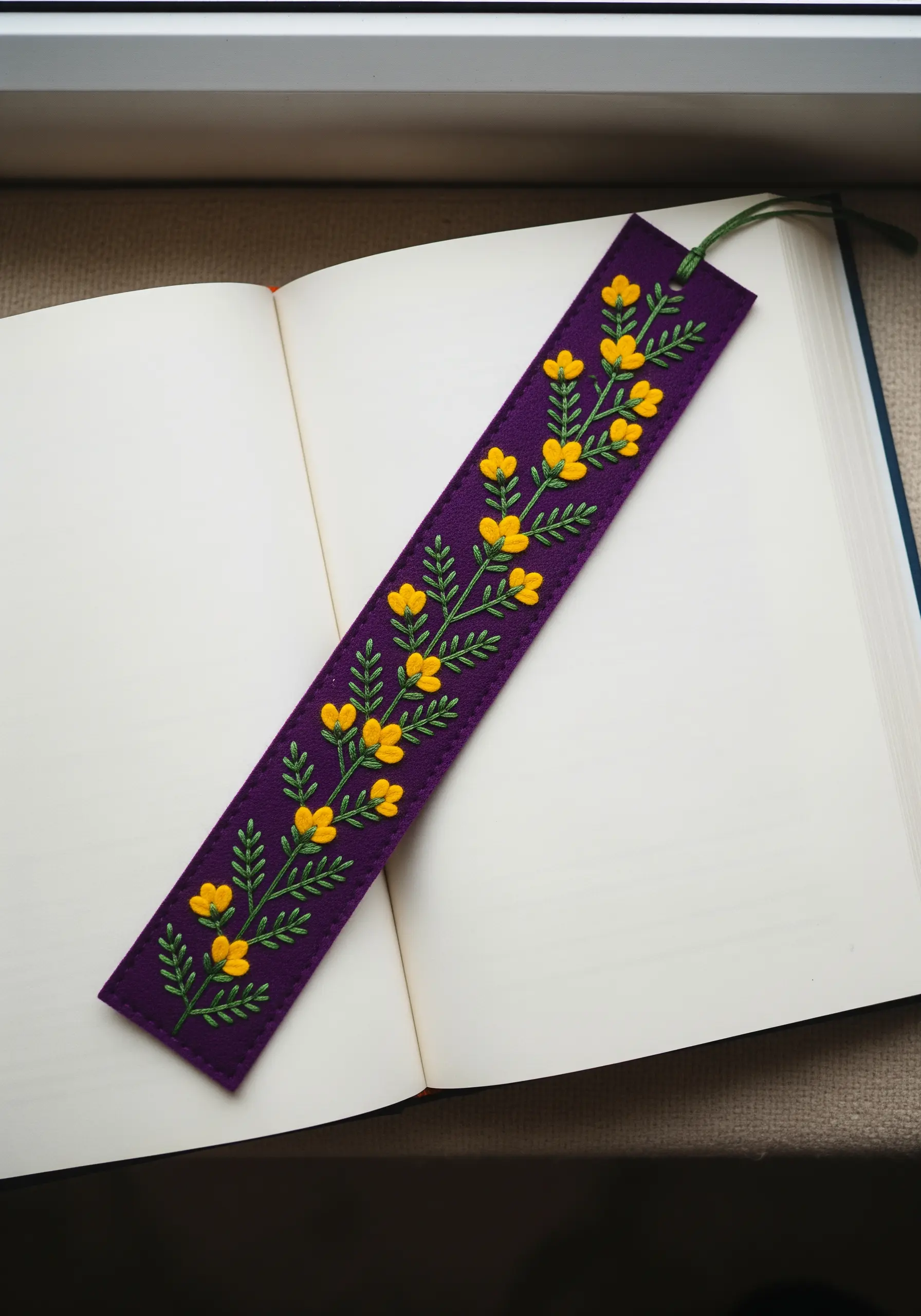 Yellow buttercups and green leaves embroidered on a purple felt bookmark.