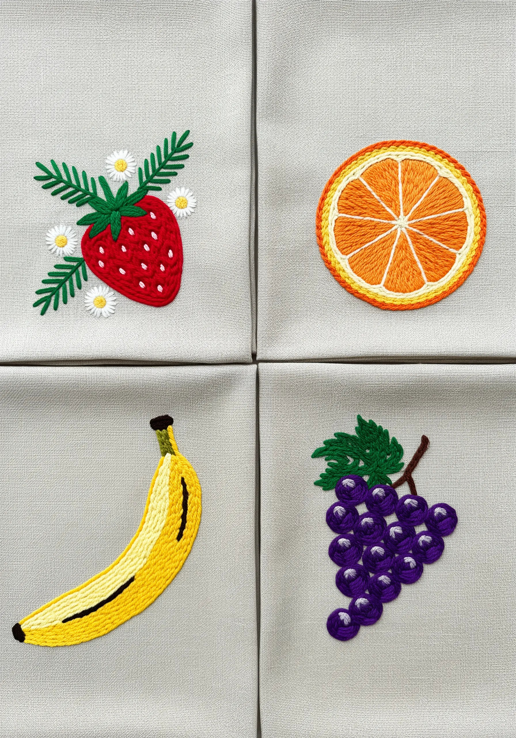 Four embroidered fruit motifs: strawberry, orange slice, banana, and grapes.