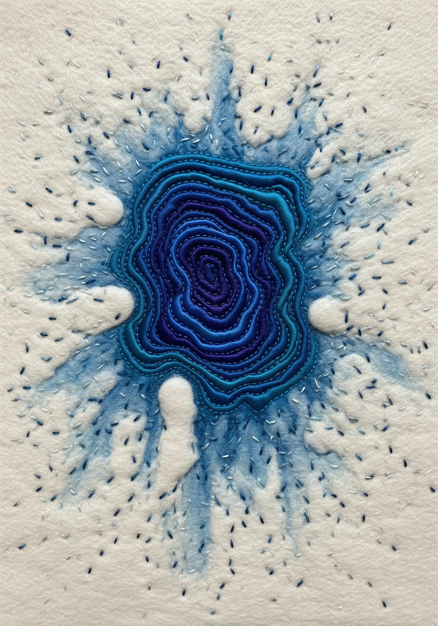 Abstract embroidery over a watercolor bleed effect, with dense blue stitches in the center and sparse stitches radiating out.