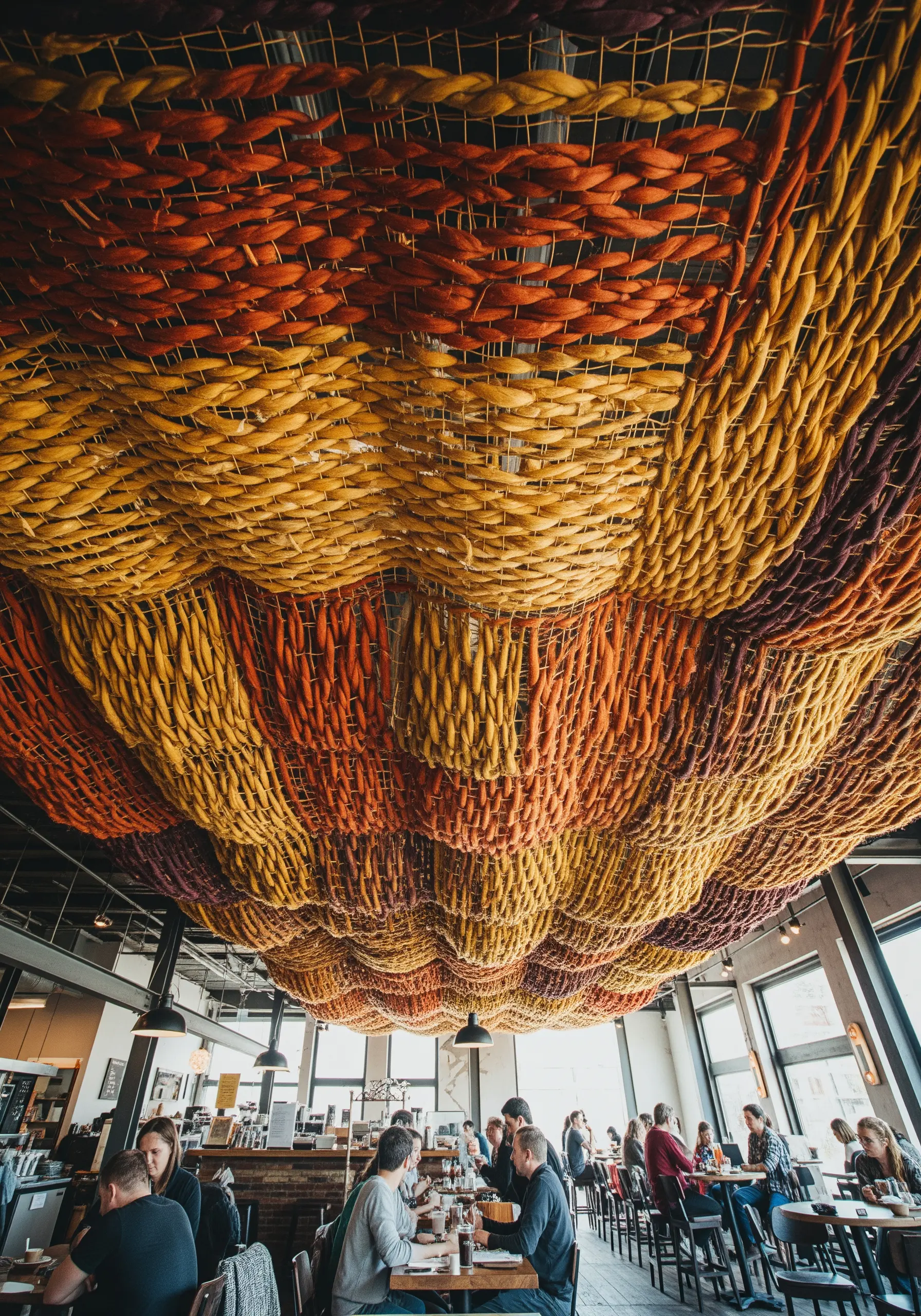 A ceiling covered in a woven tapestry of thick, chunky wool roving in warm autumn colors.